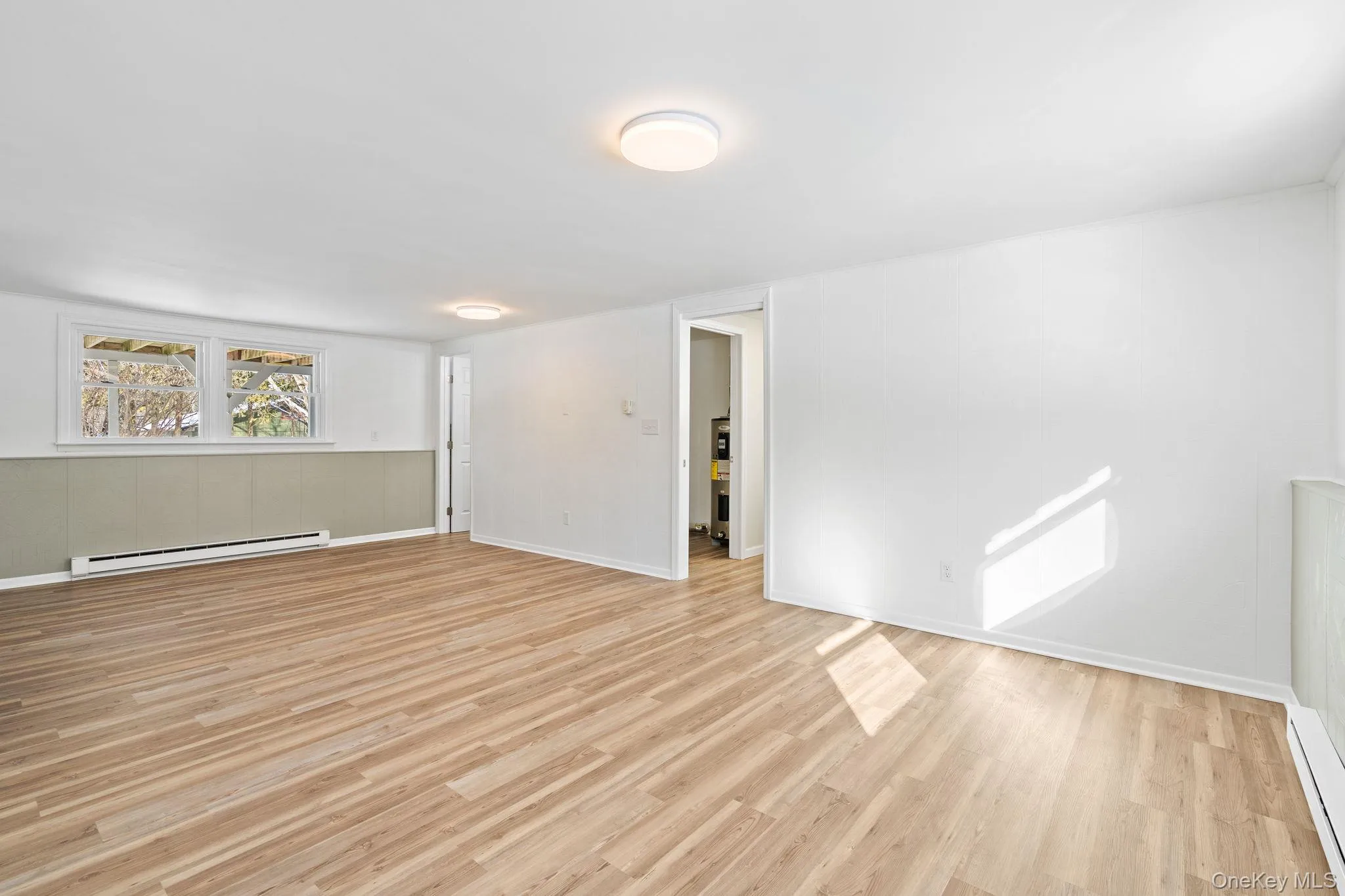 Spare room featuring light wood-type flooring and a baseboard heating unit Spare room featuring light wood-type flooring and a baseboard heating unit