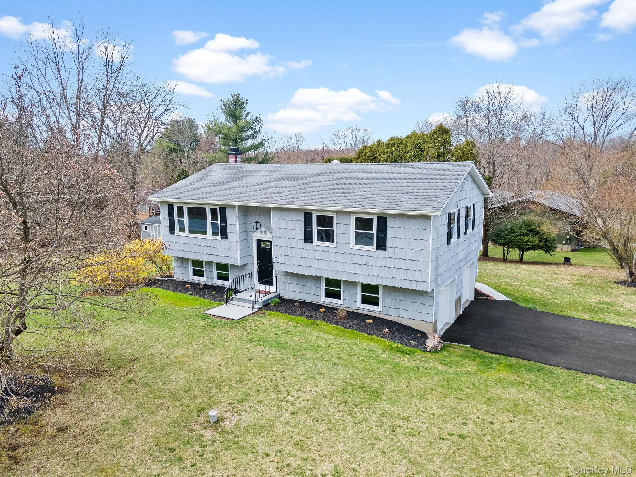 Bi-level home featuring a chimney, driveway, a front yard, a garage, and roof with shingles Bi-level home featuring a chimney, driveway, a front yard, a garage, and roof with shingles