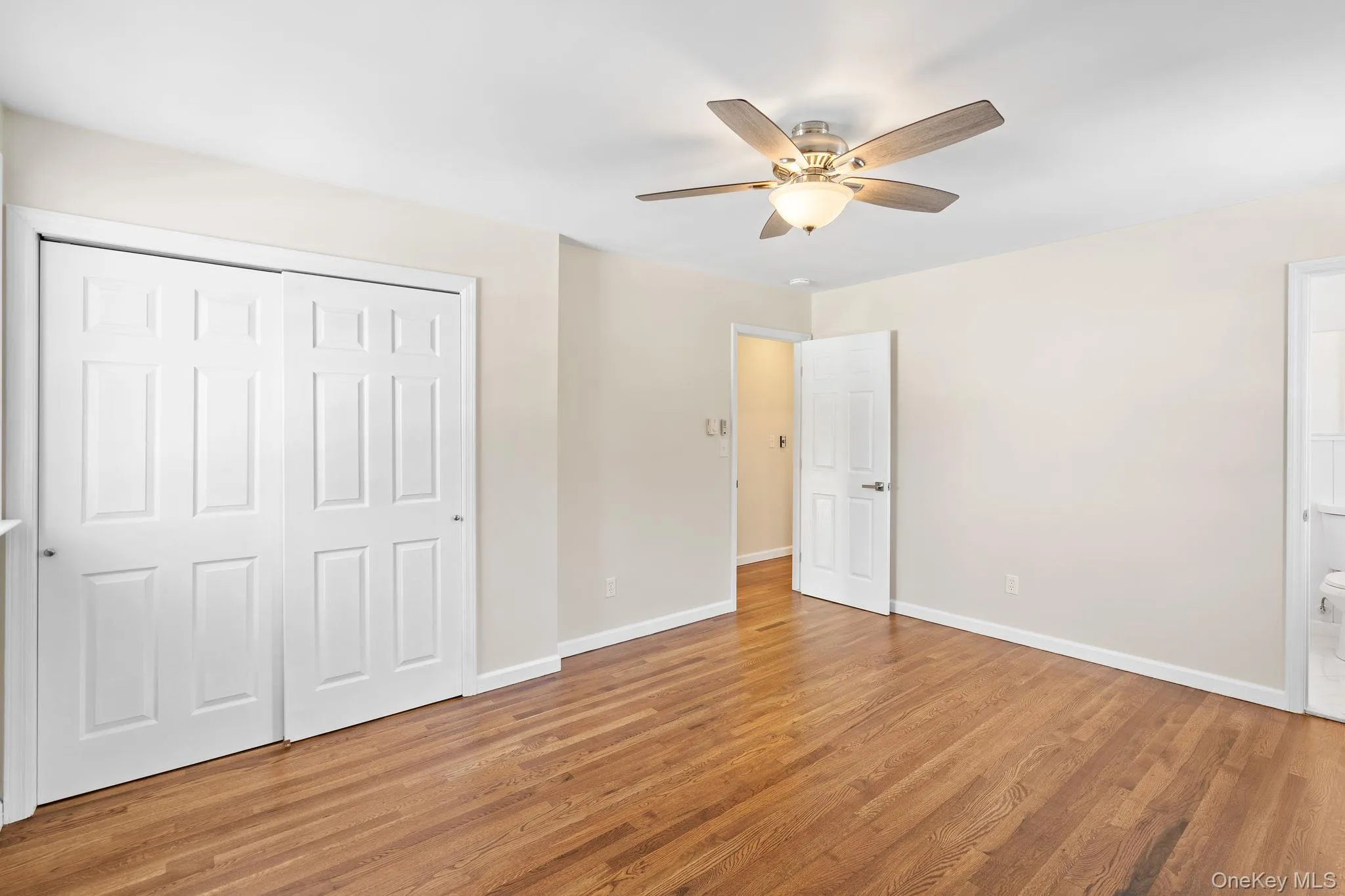Unfurnished bedroom with wood-type flooring, connected bathroom, ceiling fan, and a closet Unfurnished bedroom with wood-type flooring, connected bathroom, ceiling fan, and a closet