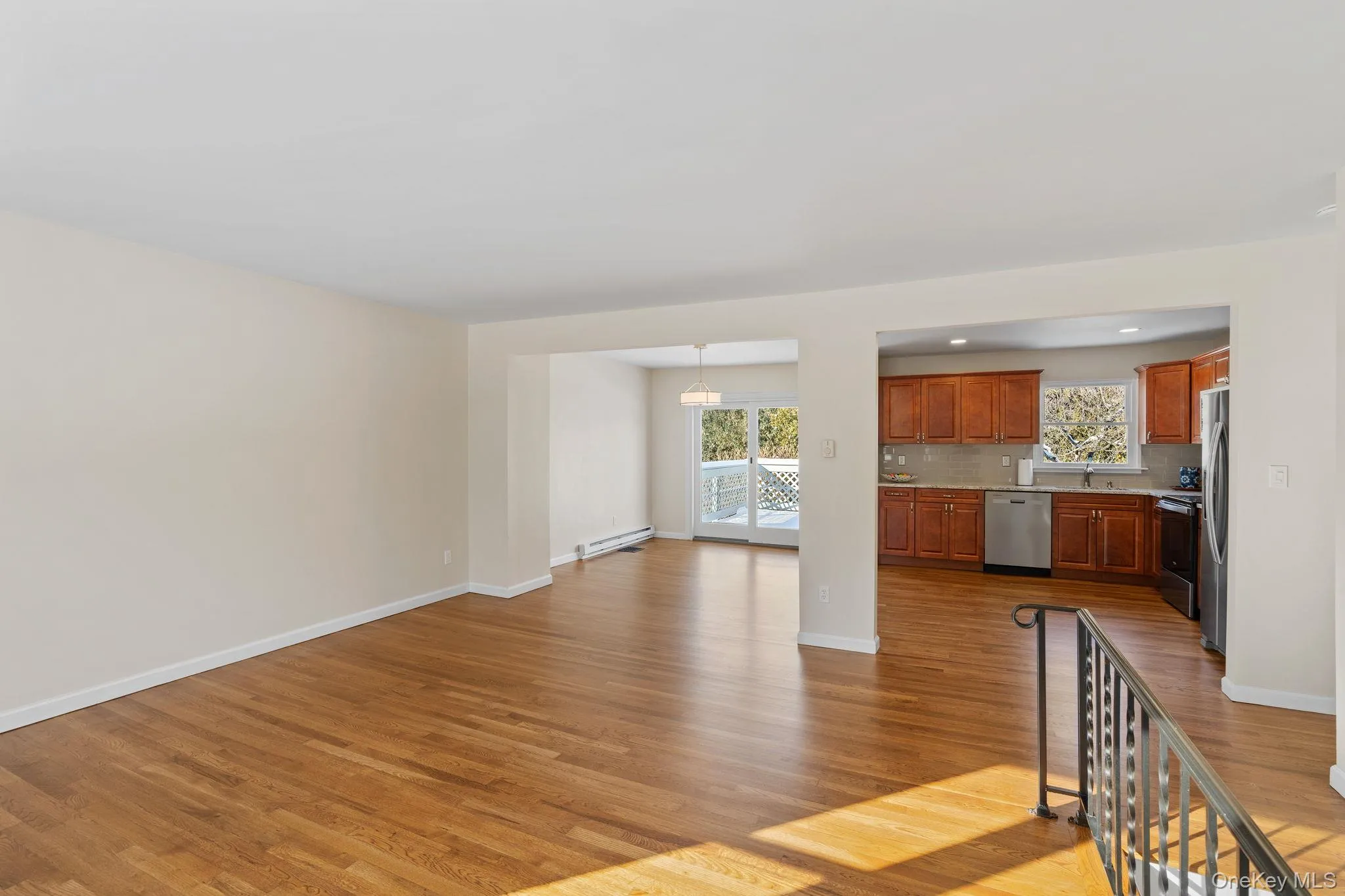 Unfurnished living room featuring a chandelier, a baseboard heating unit, sink, and light wood-type flooring Unfurnished living room featuring a chandelier, a baseboard heating unit, sink, and light wood-type flooring