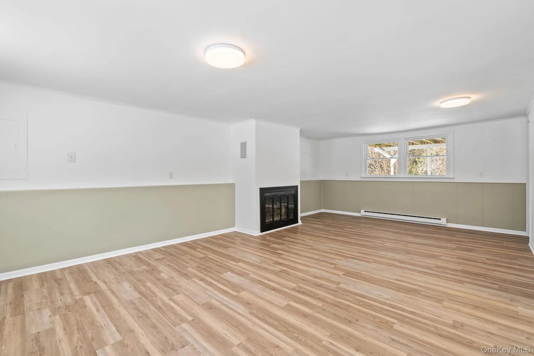 Basement with a baseboard radiator and light hardwood / wood-style flooring Basement with a baseboard radiator and light hardwood / wood-style flooring