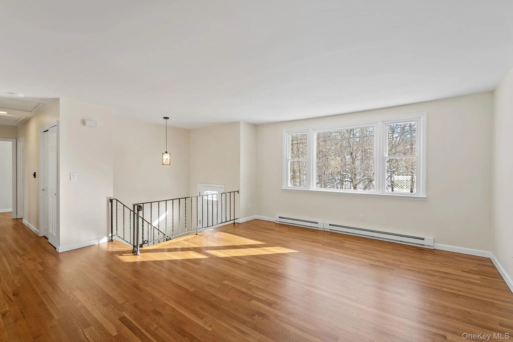 Empty room with hardwood / wood-style flooring and a baseboard heating unit Empty room with hardwood / wood-style flooring and a baseboard heating unit