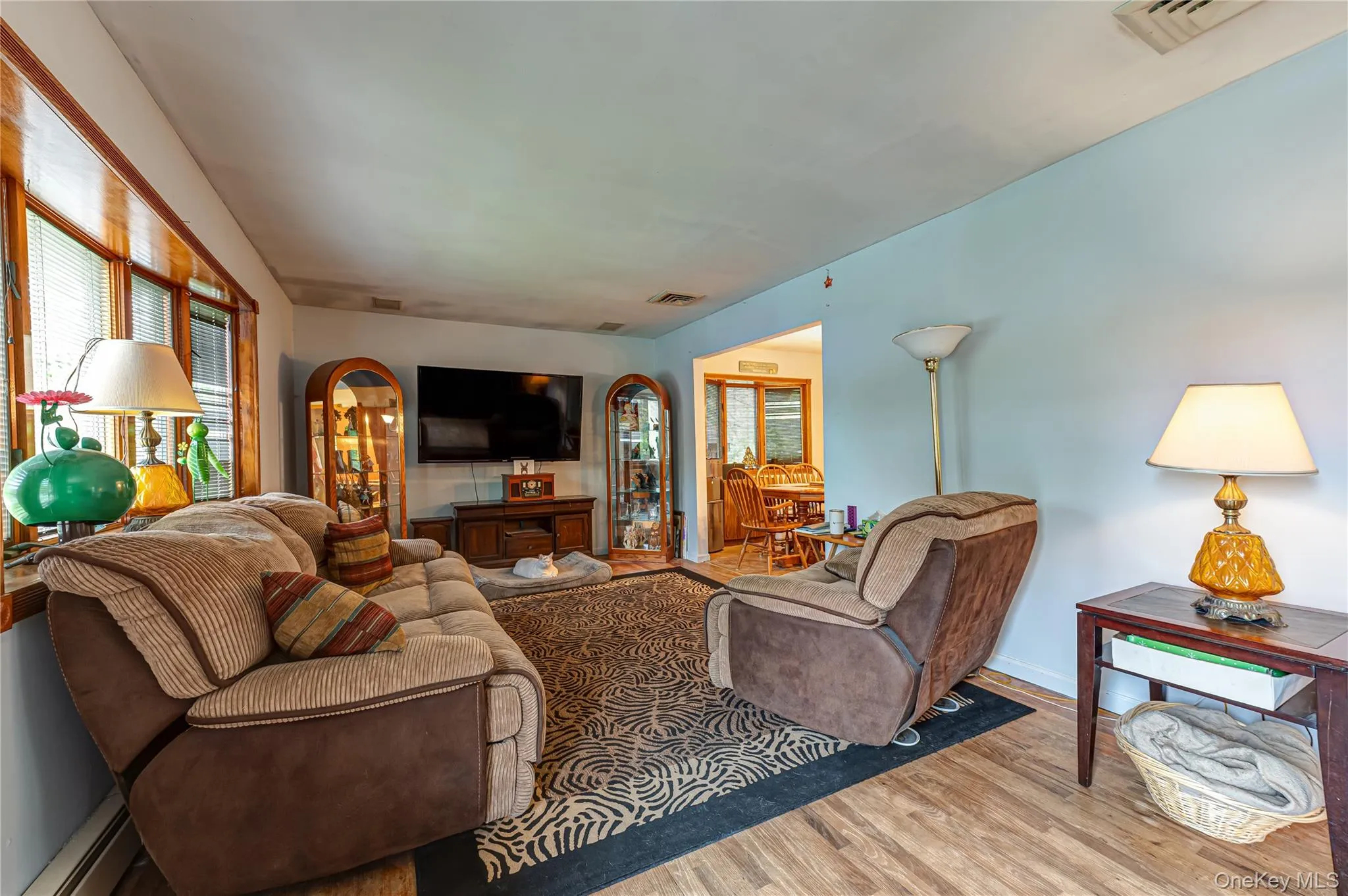 Living area featuring wood-flooring, a large bay window with wood trim, light blue wall paint. Living area featuring wood-flooring, a large bay window with wood trim, light blue wall paint.