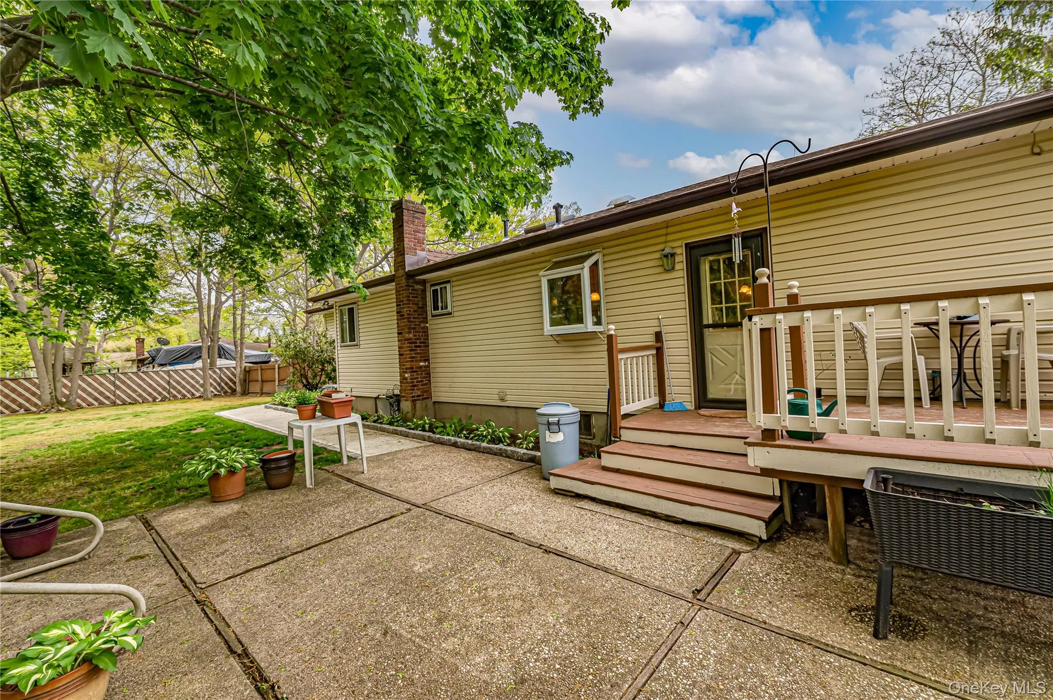 Rear exterior with a wood-finish deck and steps, leading to a concrete patio Rear exterior with a wood-finish deck and steps, leading to a concrete patio