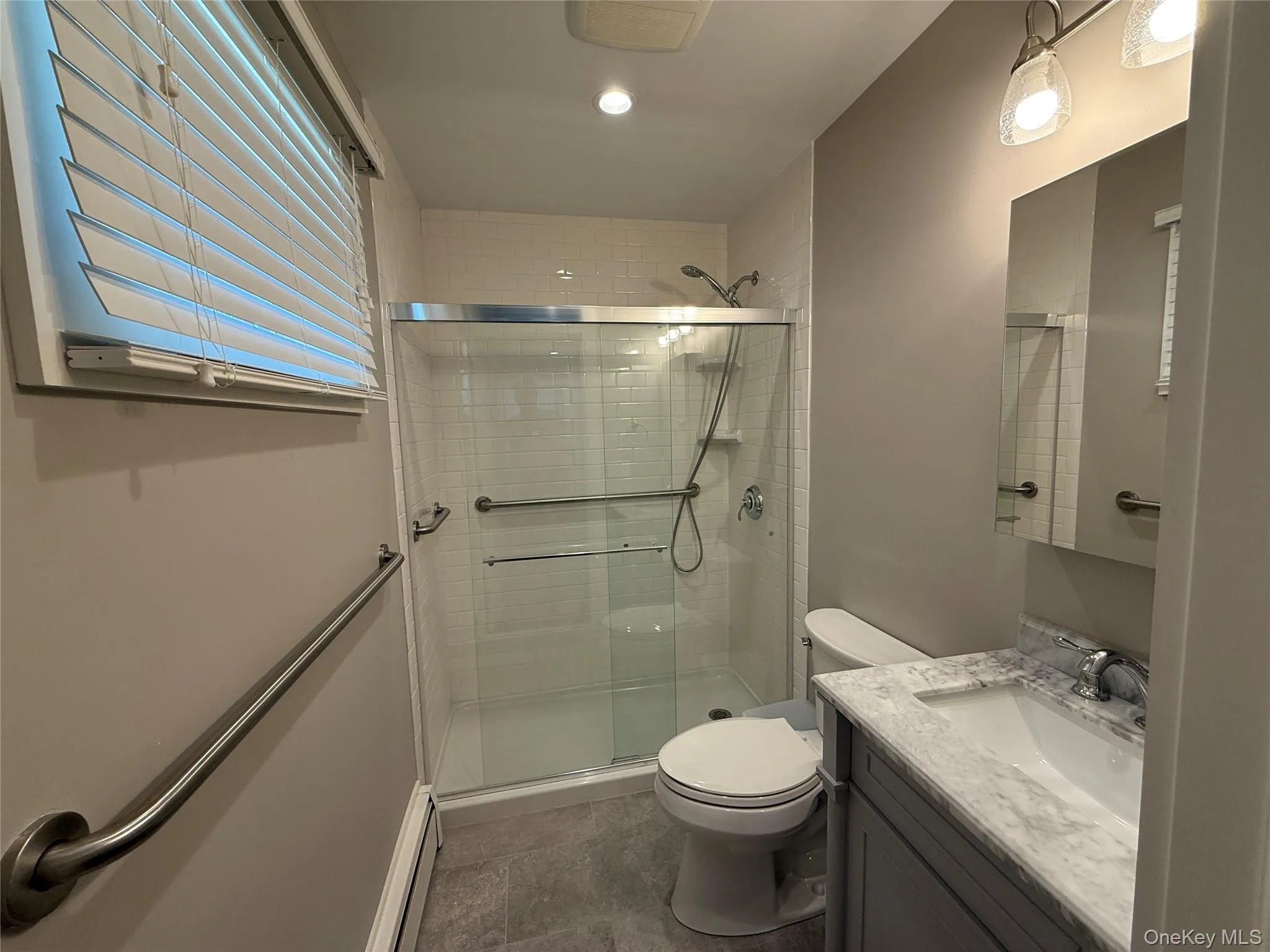 Bathroom with toilet, a shower stall, a baseboard radiator, and vanity Bathroom with toilet, a shower stall, a baseboard radiator, and vanity