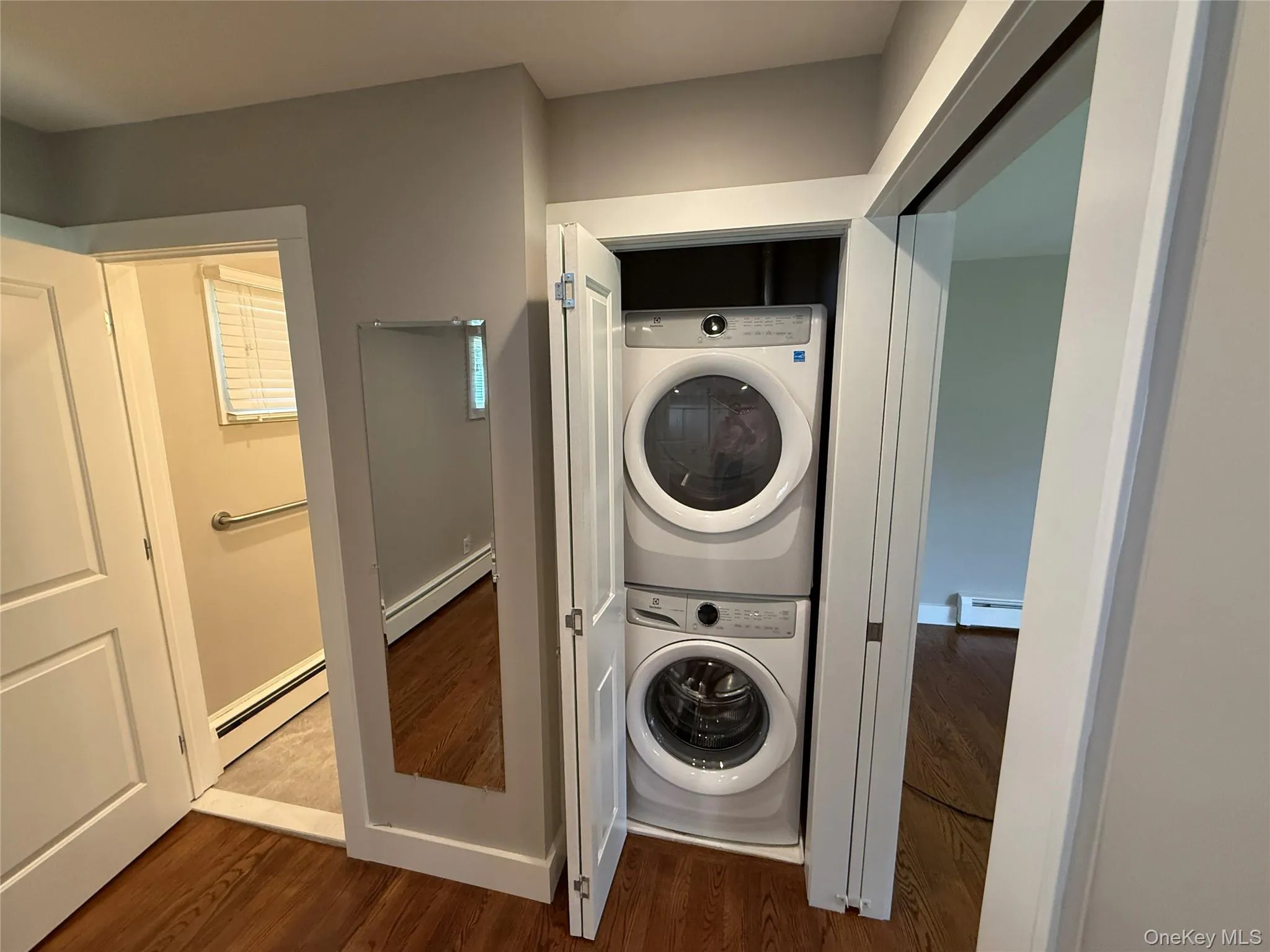 Laundry area featuring laundry area, stacked washer and clothes dryer, and a baseboard radiator Laundry area featuring laundry area, stacked washer and clothes dryer, and a baseboard radiator