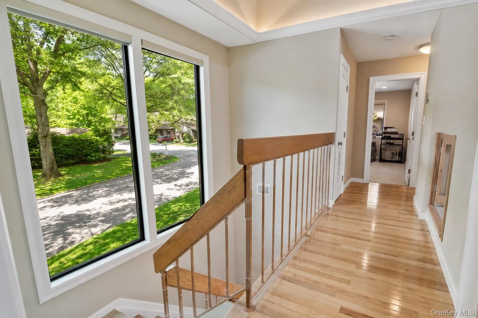 Hardwood flooring extending through the hallway, featuring a wood handrail with walls of windows! Hardwood flooring extending through the hallway, featuring a wood handrail with walls of windows!