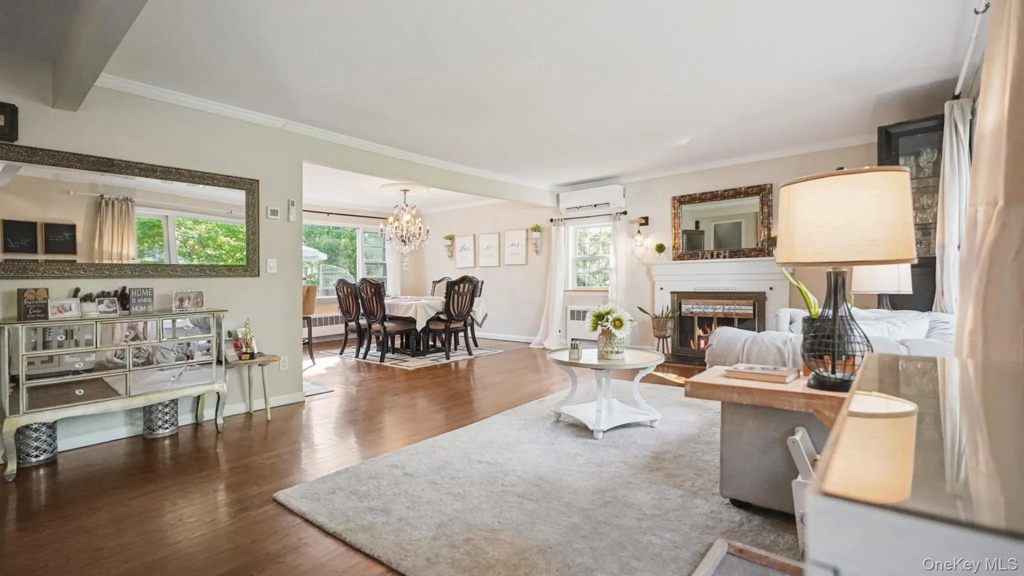 Hardwood flooring throughout a living space featuring a fireplace with a decorative mantel and a built-in mirror Hardwood flooring throughout a living space featuring a fireplace with a decorative mantel and a built-in mirror
