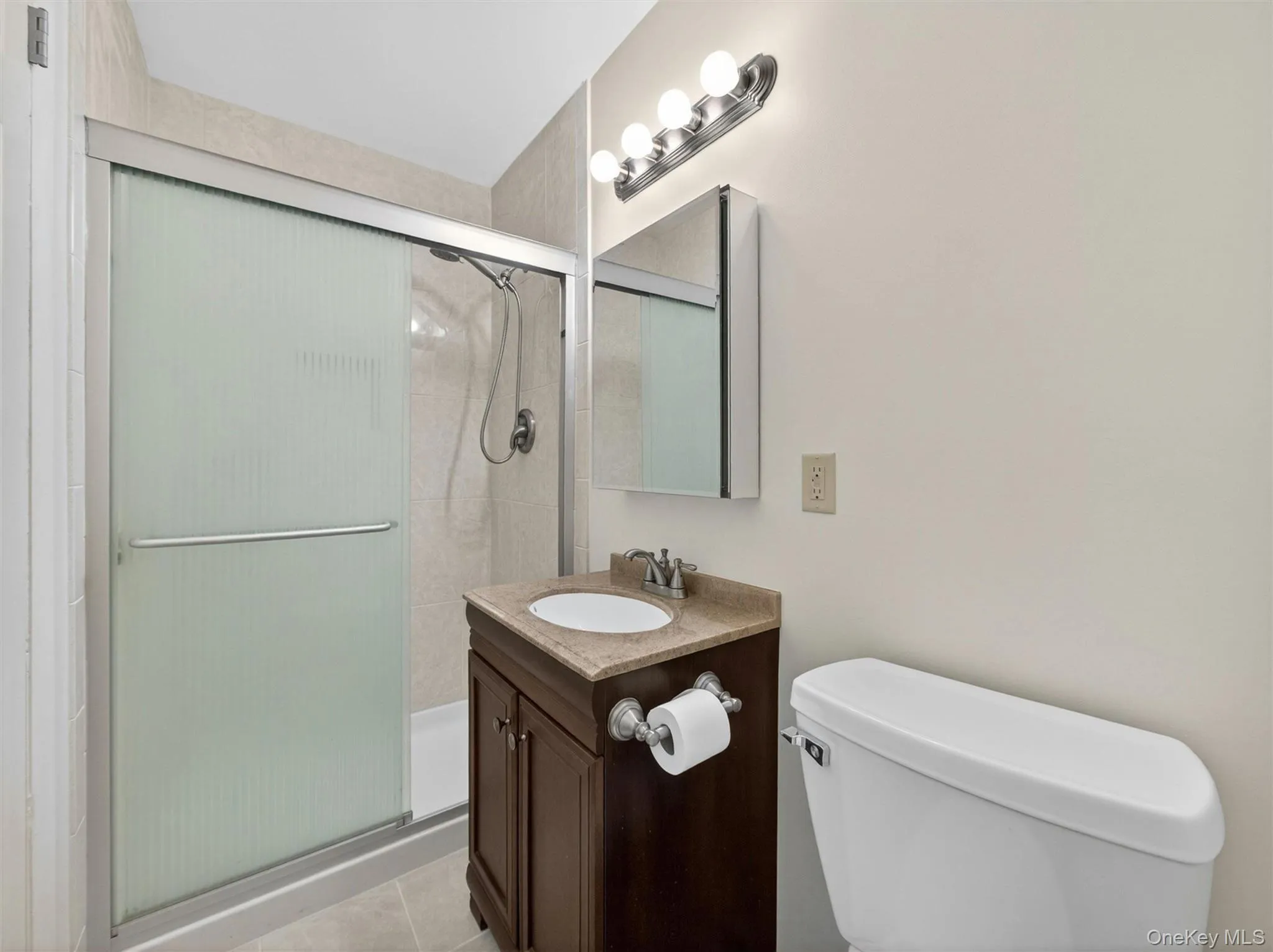 Private ensuite bathroom featuring a walk-in shower and vanity storage. Private ensuite bathroom featuring a walk-in shower and vanity storage.
