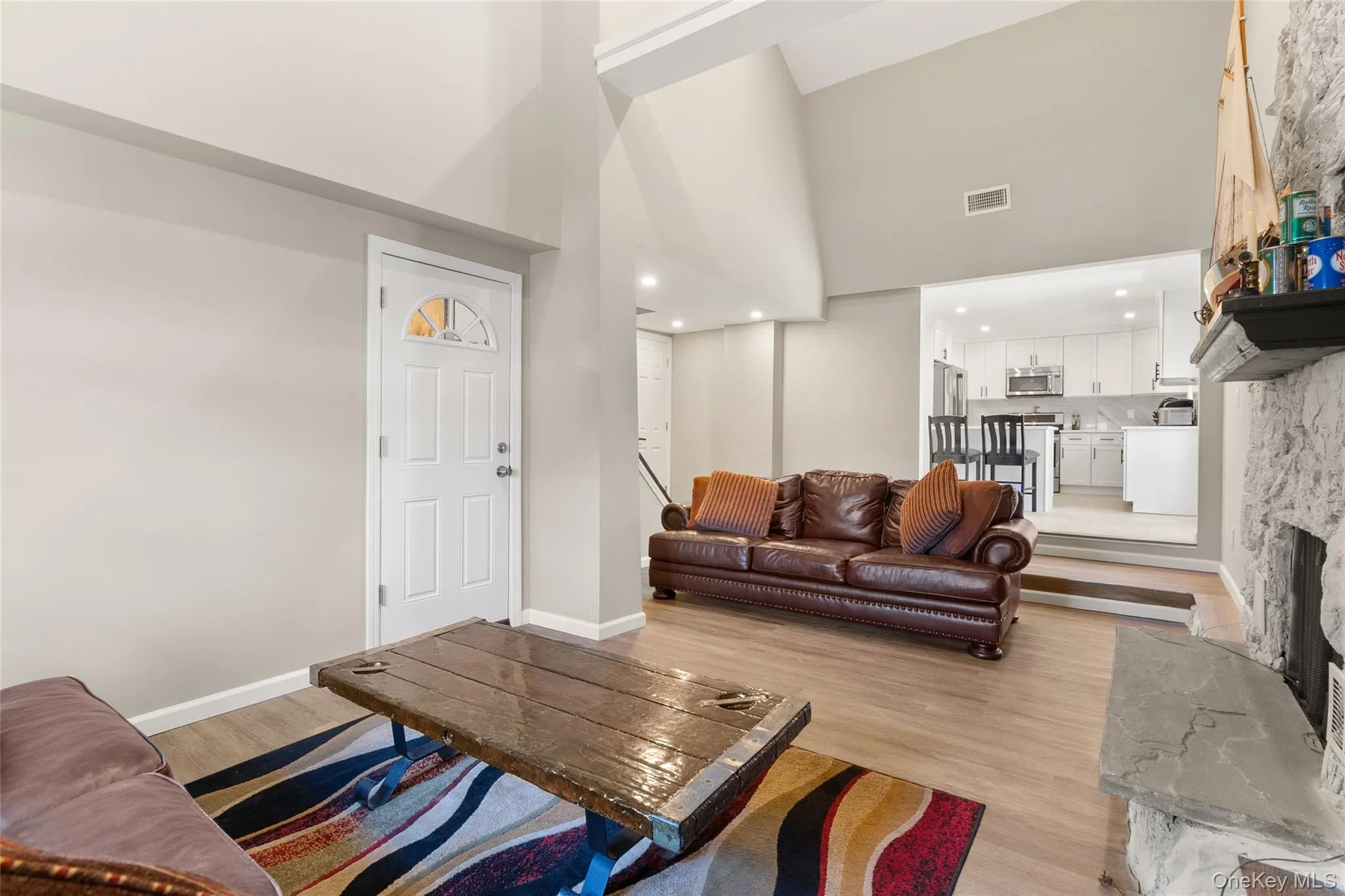 Living area/Den featuring vaulted ceilings, wood-finish flooring, a stone-faced fireplace with a stone hearth. Living area/Den featuring vaulted ceilings, wood-finish flooring, a stone-faced fireplace with a stone hearth.