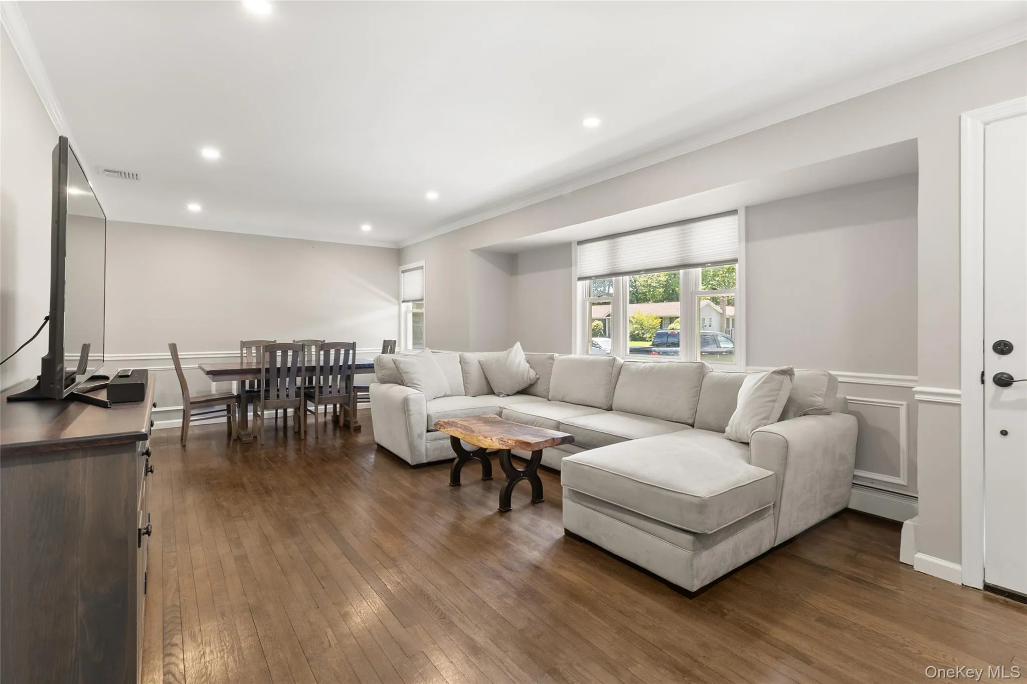 Open-concept living area featuring rich wood-finish flooring, recessed lighting, and crown molding Open-concept living area featuring rich wood-finish flooring, recessed lighting, and crown molding