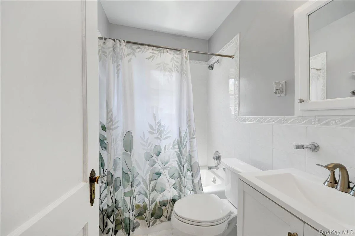 Bathroom featuring a white vanity with integrated sink, bronze-finish faucet, and a wall-mounted mirror Bathroom featuring a white vanity with integrated sink, bronze-finish faucet, and a wall-mounted mirror