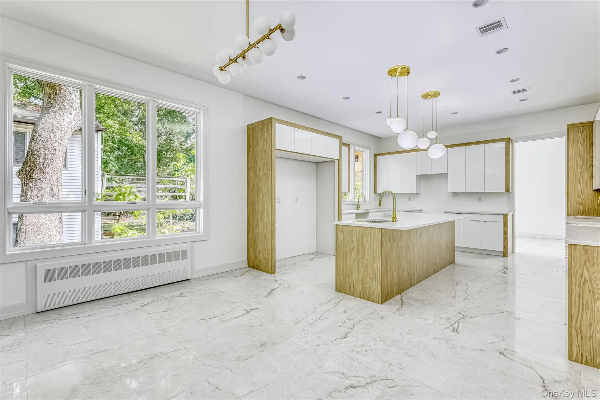 Kitchen featuring white cabinets, radiator, an island with sink, decorative light fixtures, and recessed lighting Kitchen featuring white cabinets, radiator, an island with sink, decorative light fixtures, and recessed lighting