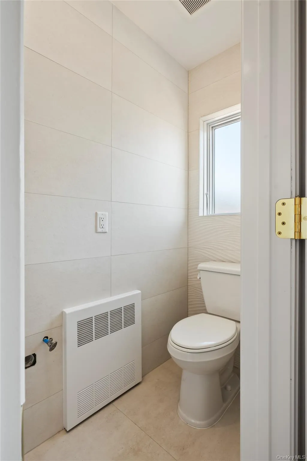 Bathroom featuring light tile patterned floors, tile walls, and heating unit Bathroom featuring light tile patterned floors, tile walls, and heating unit