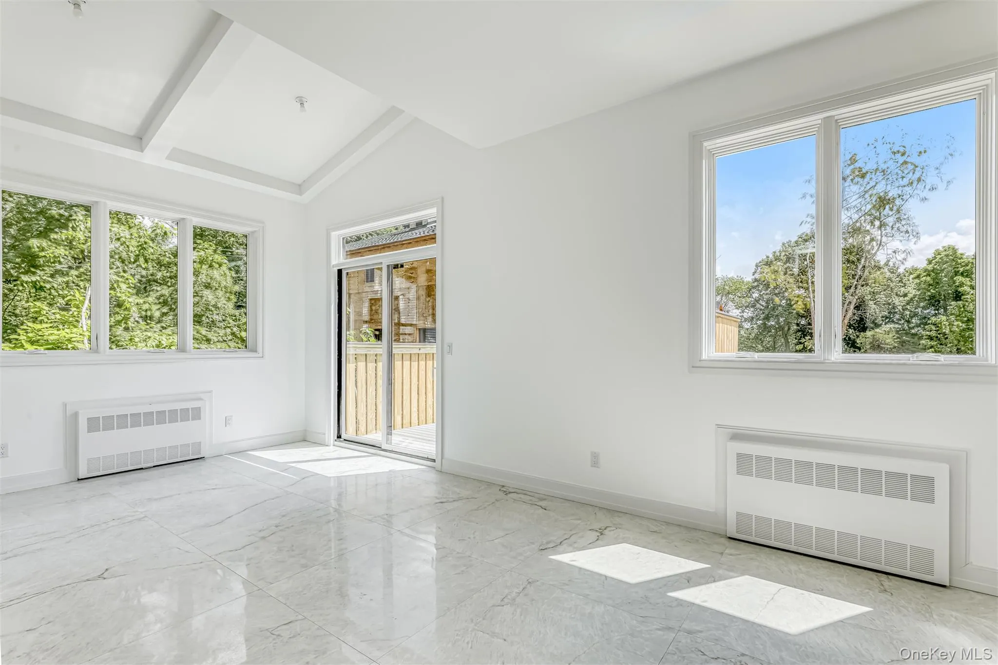 Spare room featuring radiator heating unit, light marble finish flooring, and lofted ceiling Spare room featuring radiator heating unit, light marble finish flooring, and lofted ceiling