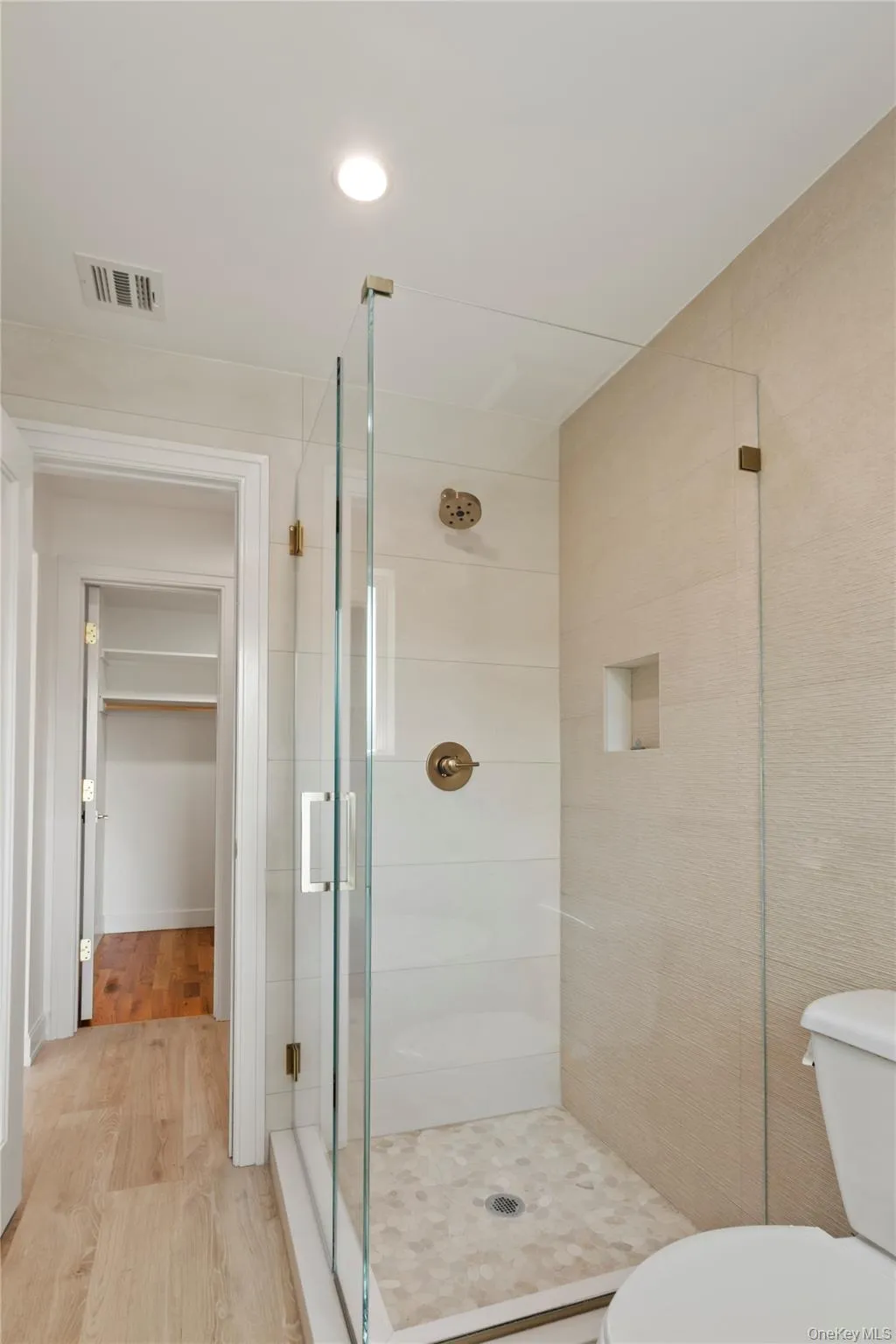 Bathroom featuring a shower stall, light wood-style flooring, a spacious closet, and recessed lighting Bathroom featuring a shower stall, light wood-style flooring, a spacious closet, and recessed lighting