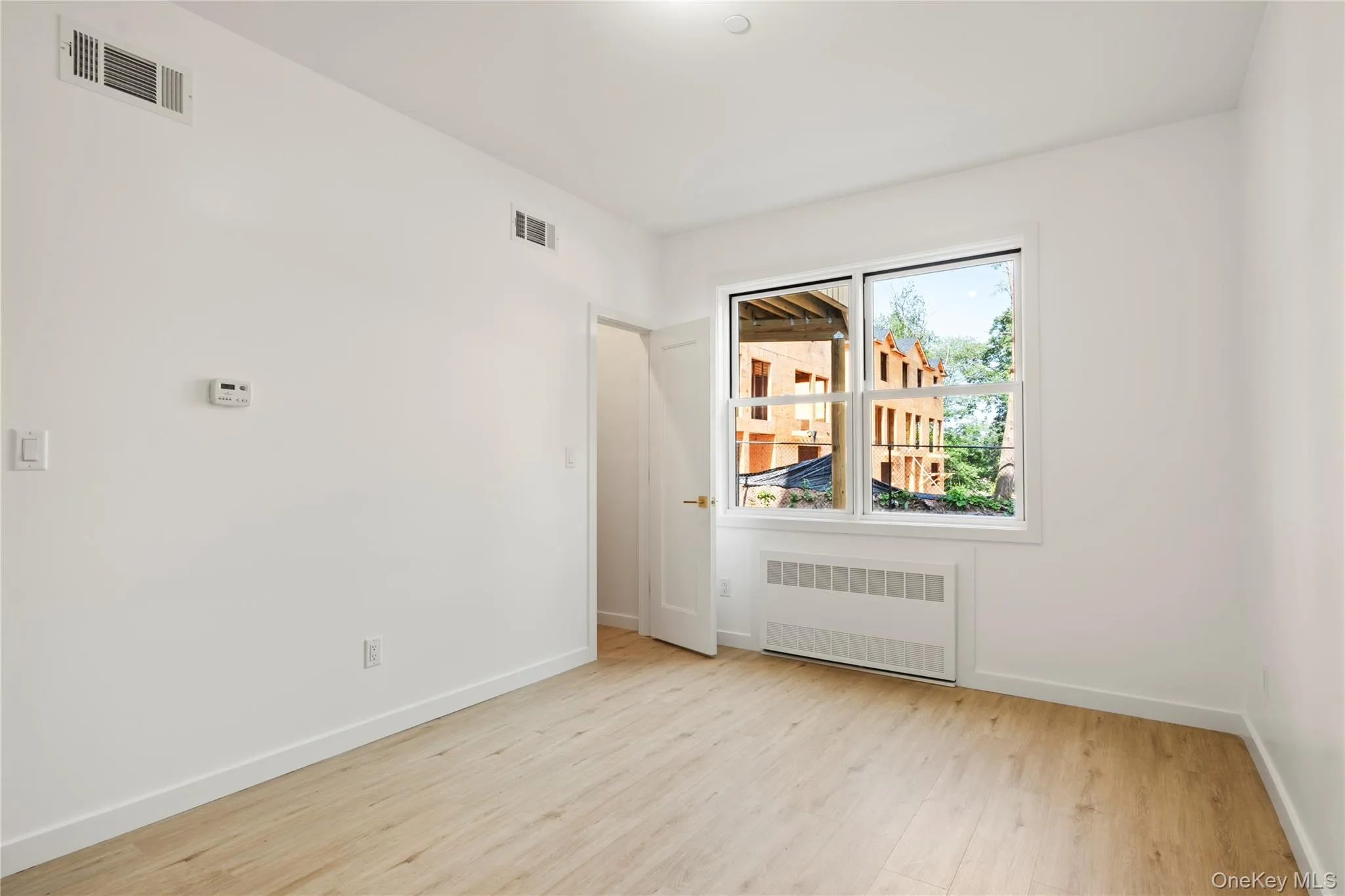 Empty room with radiator heating unit and light wood-style floors Empty room with radiator heating unit and light wood-style floors