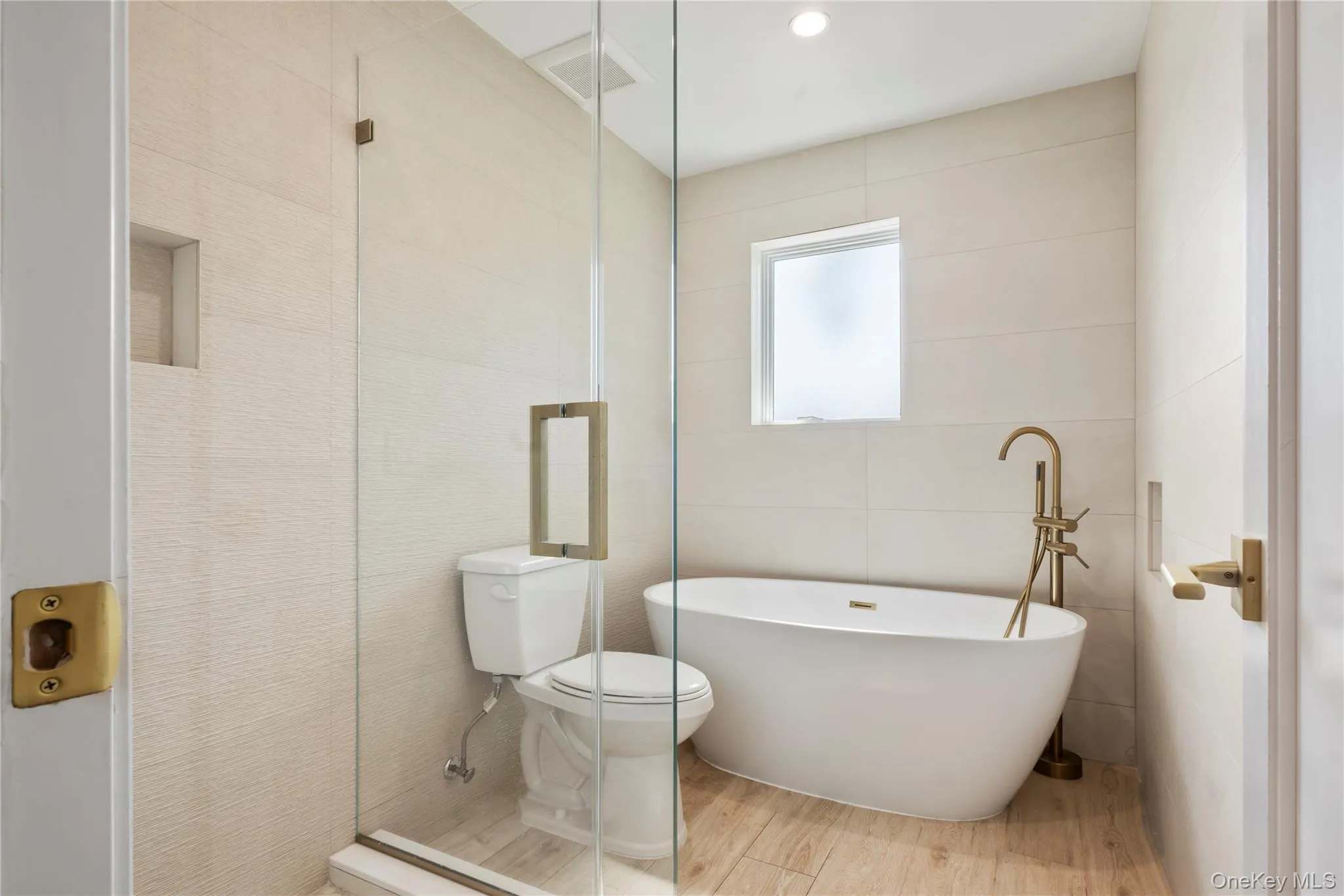 Bathroom with tile walls, wood finished floors, a soaking tub, a shower stall, and recessed lighting Bathroom with tile walls, wood finished floors, a soaking tub, a shower stall, and recessed lighting