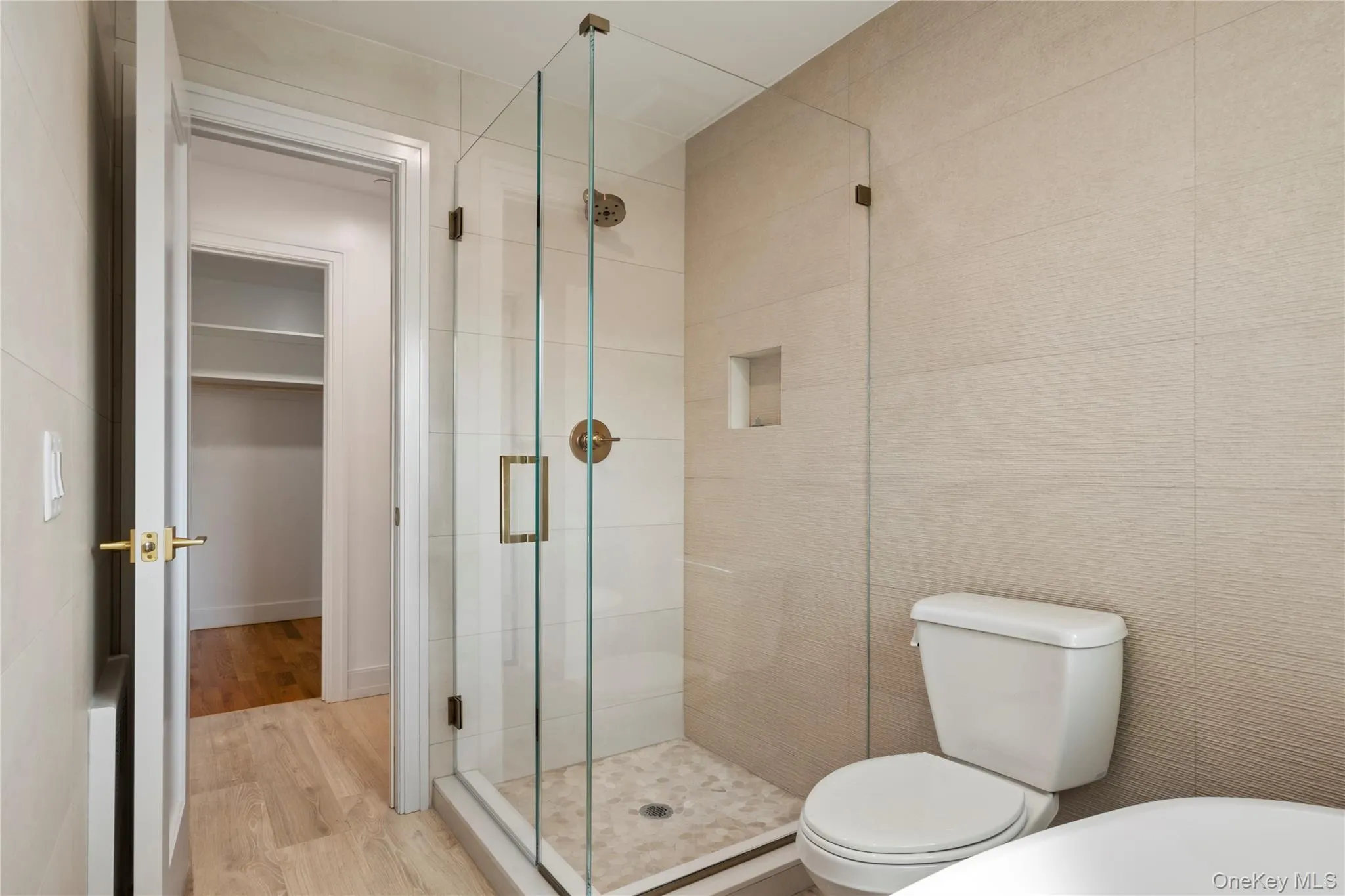 Full bathroom with wood finished floors, a stall shower, and a spacious closet Full bathroom with wood finished floors, a stall shower, and a spacious closet