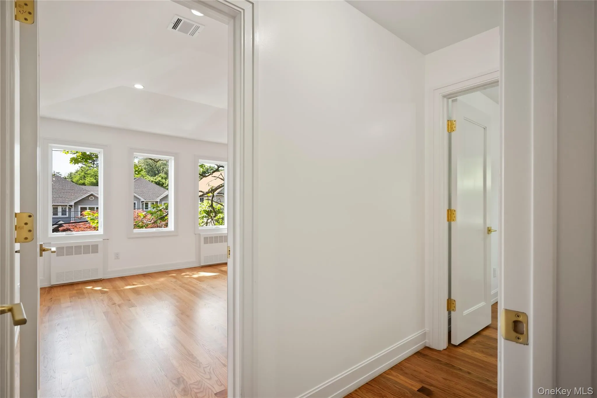 Hallway with light wood-style flooring, radiator, and recessed lighting Hallway with light wood-style flooring, radiator, and recessed lighting