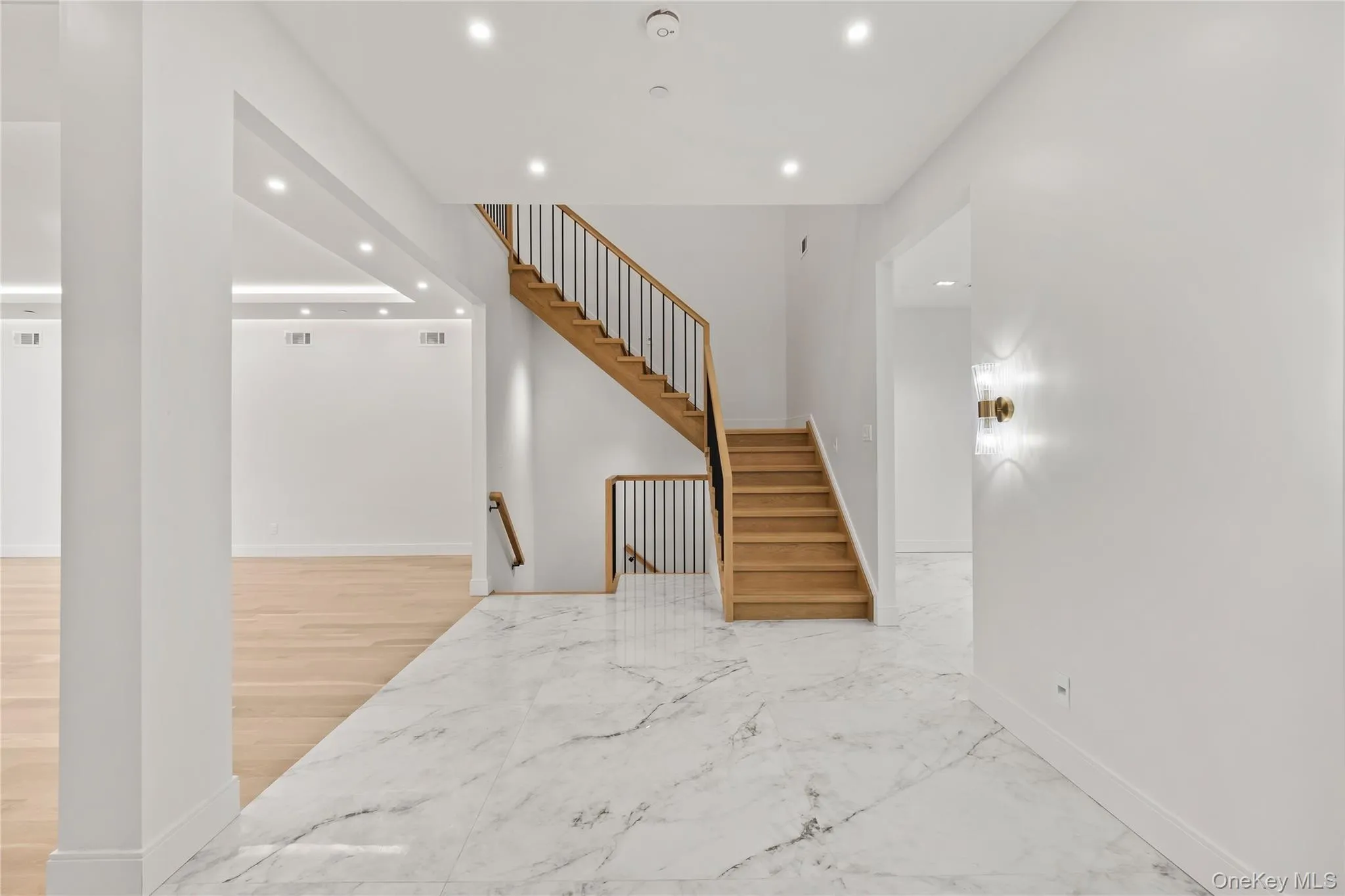 Marble-finish tile flooring throughout the entry with radiant heat, complemented by a wood staircase with black metal balusters Marble-finish tile flooring throughout the entry with radiant heat, complemented by a wood staircase with black metal balusters