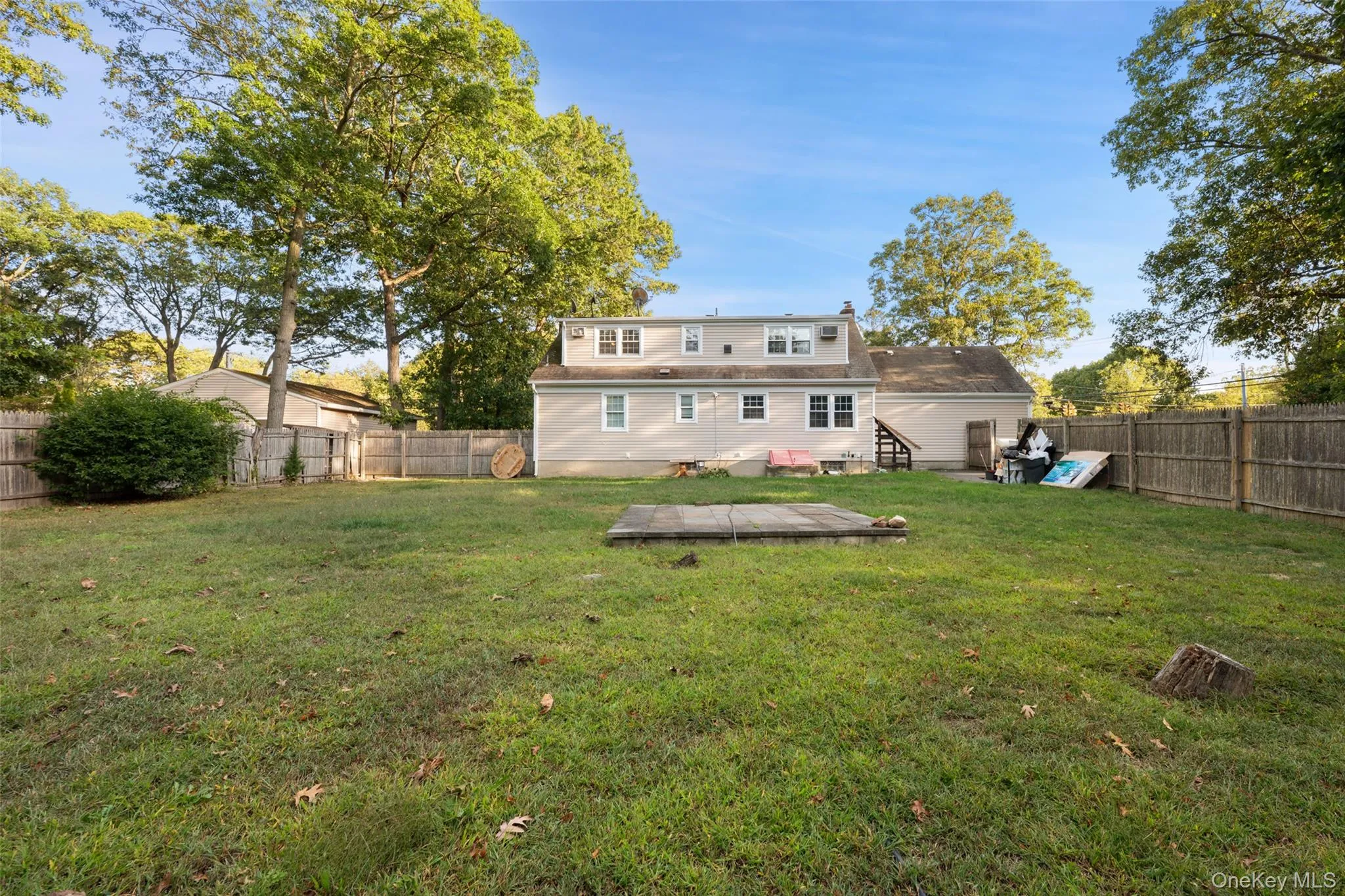 Expansive backyard featuring a manicured lawn, established perimeter fencing, mature trees, and a concrete patio Expansive backyard featuring a manicured lawn, established perimeter fencing, mature trees, and a concrete patio