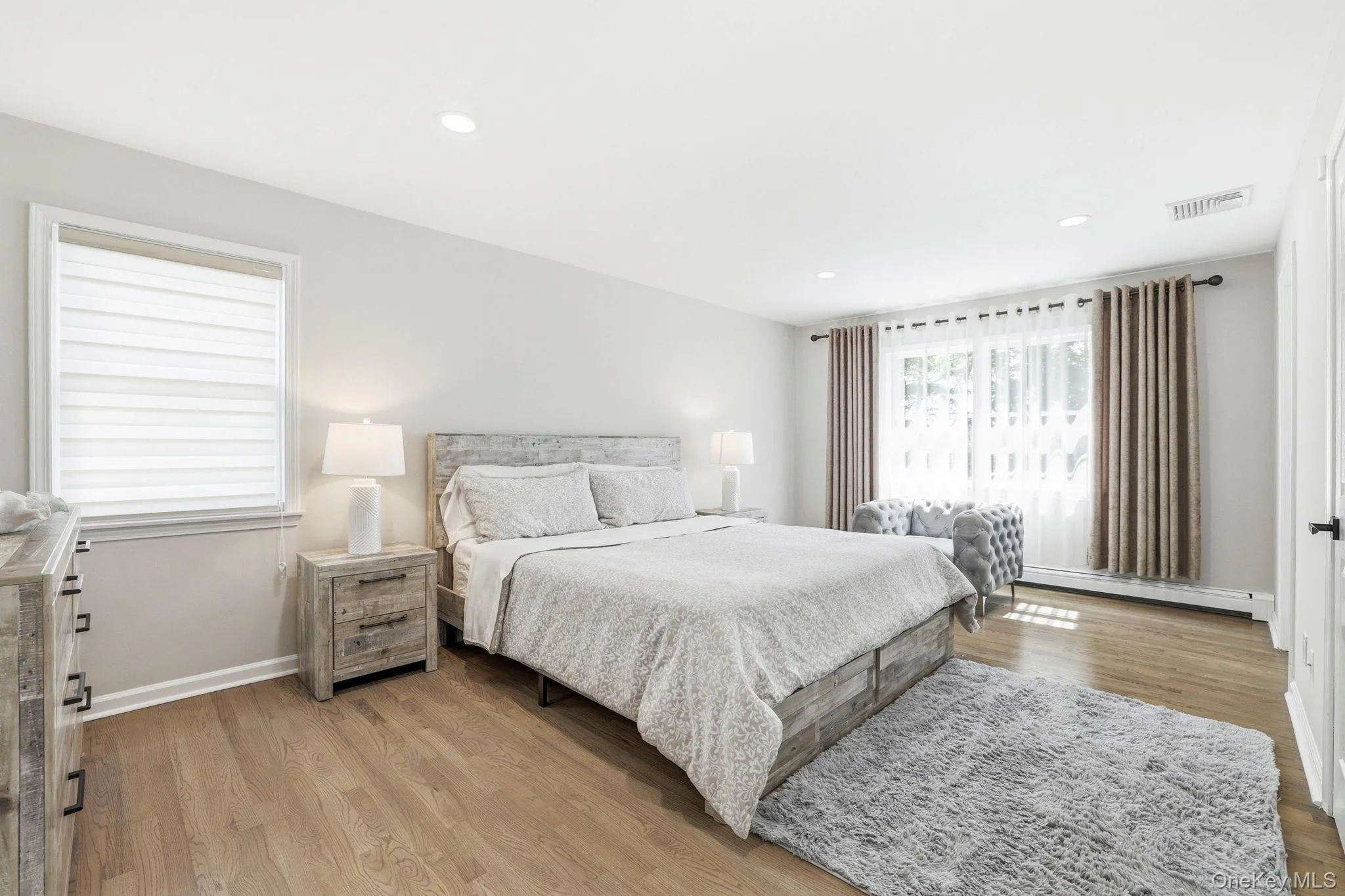 Spacious room featuring wood-finish flooring, recessed lighting, and ample natural light from two windows Spacious room featuring wood-finish flooring, recessed lighting, and ample natural light from two windows