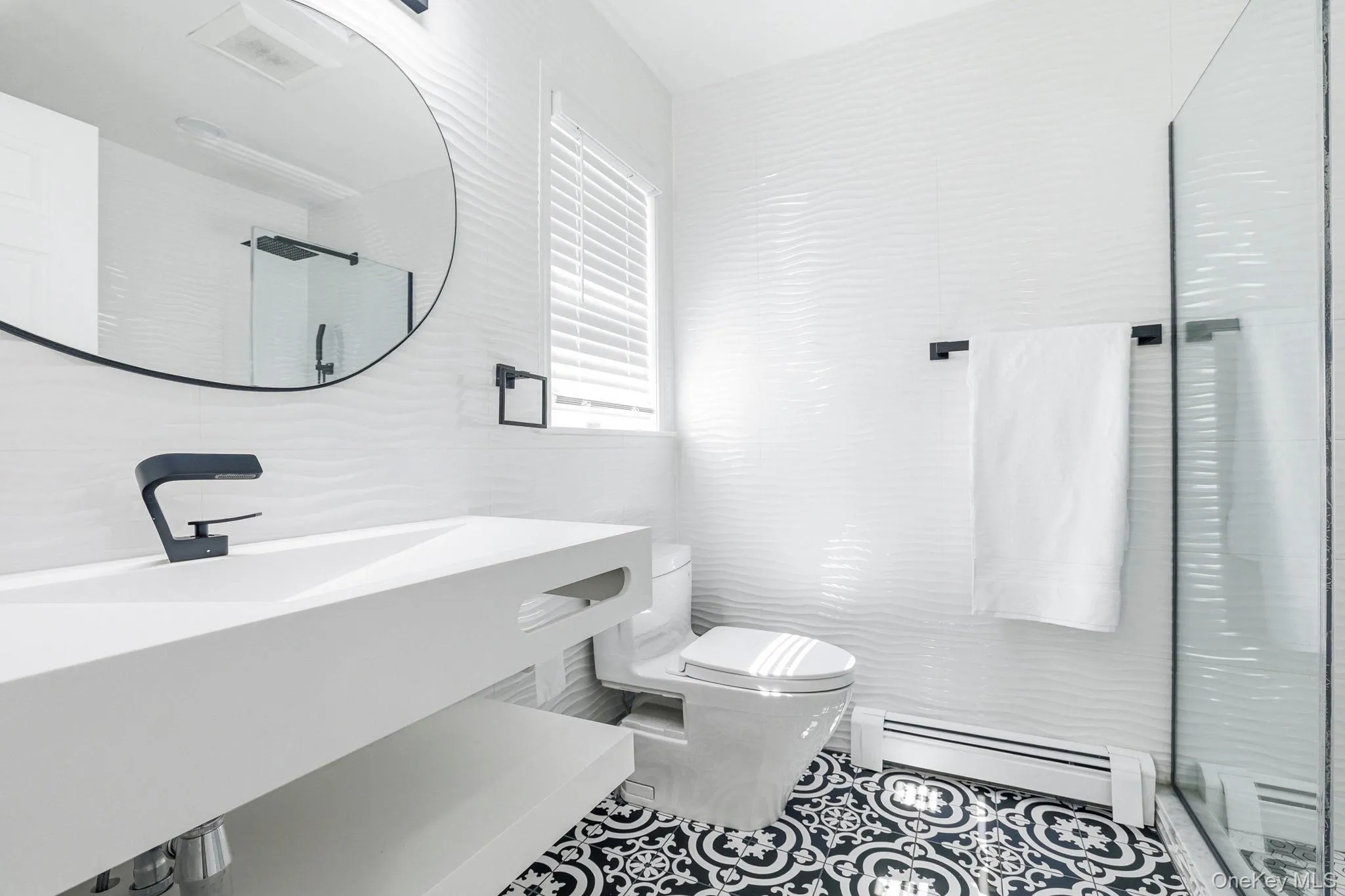 Modern bathroom featuring a floating white vanity with an integrated sink and matte black faucet Modern bathroom featuring a floating white vanity with an integrated sink and matte black faucet