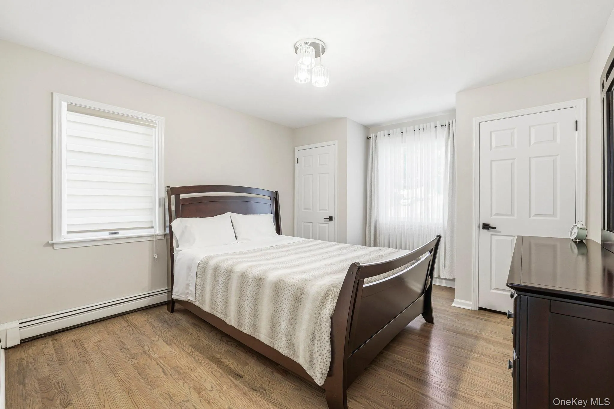 Hardwood-style flooring throughout this room, featuring light-toned wall paint and white trim Hardwood-style flooring throughout this room, featuring light-toned wall paint and white trim