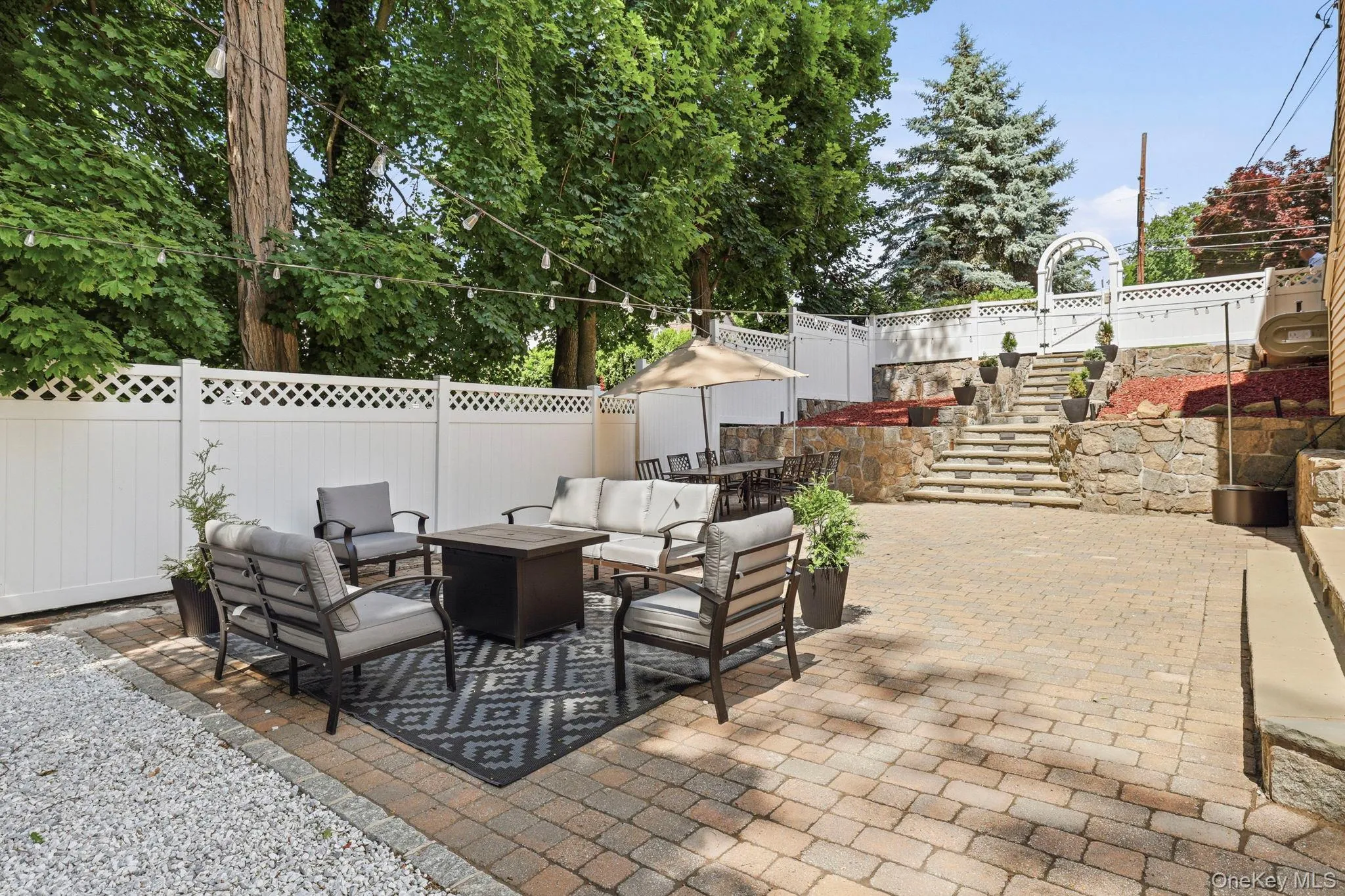 Expansive paver patio featuring a decorative stone retaining wall and an arched arbor Expansive paver patio featuring a decorative stone retaining wall and an arched arbor