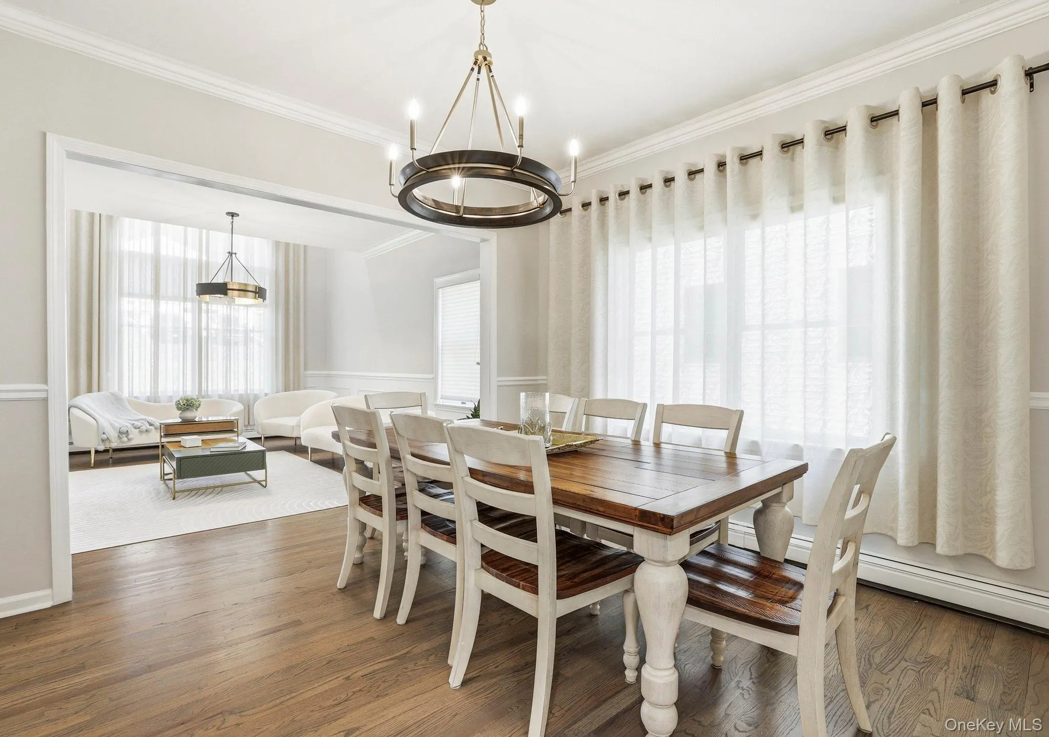 Dining area featuring wood-finish flooring, a contemporary chandelier, crown molding, and wainscoting Dining area featuring wood-finish flooring, a contemporary chandelier, crown molding, and wainscoting