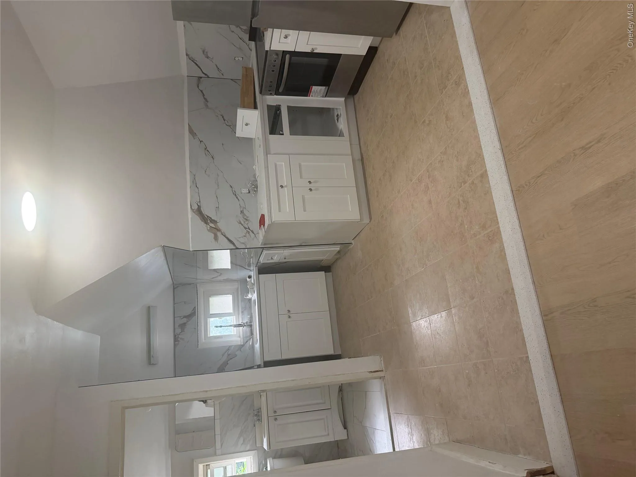 Newly renovated kitchen featuring white shaker cabinetry, an integrated stainless steel oven, a stainless steel refrigerator, and a skylight Newly renovated kitchen featuring white shaker cabinetry, an integrated stainless steel oven, a stainless steel refrigerator, and a skylight