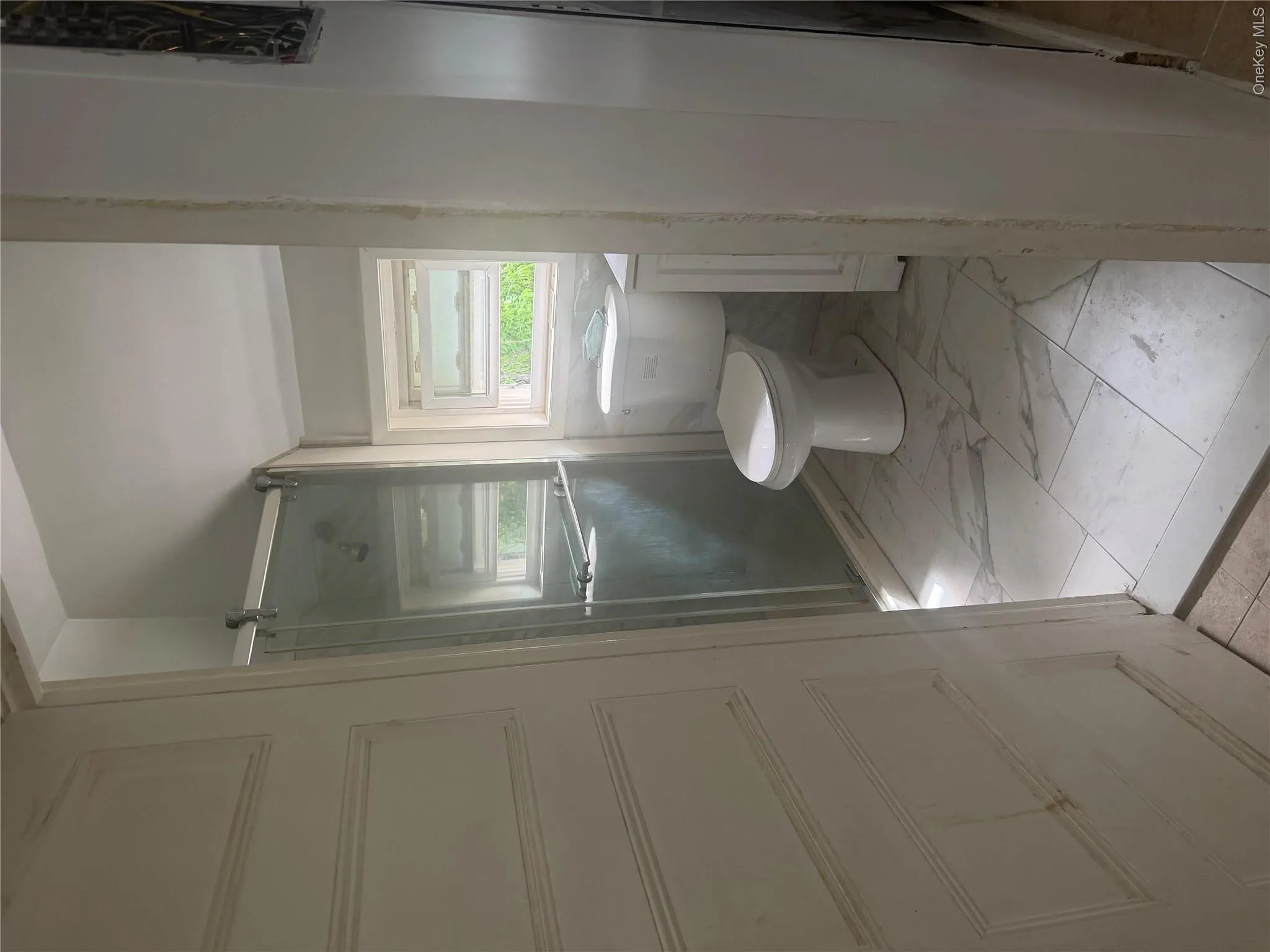 Bathroom featuring a glass-enclosed shower, white tile flooring, pedestal sink, and a built-in window Bathroom featuring a glass-enclosed shower, white tile flooring, pedestal sink, and a built-in window