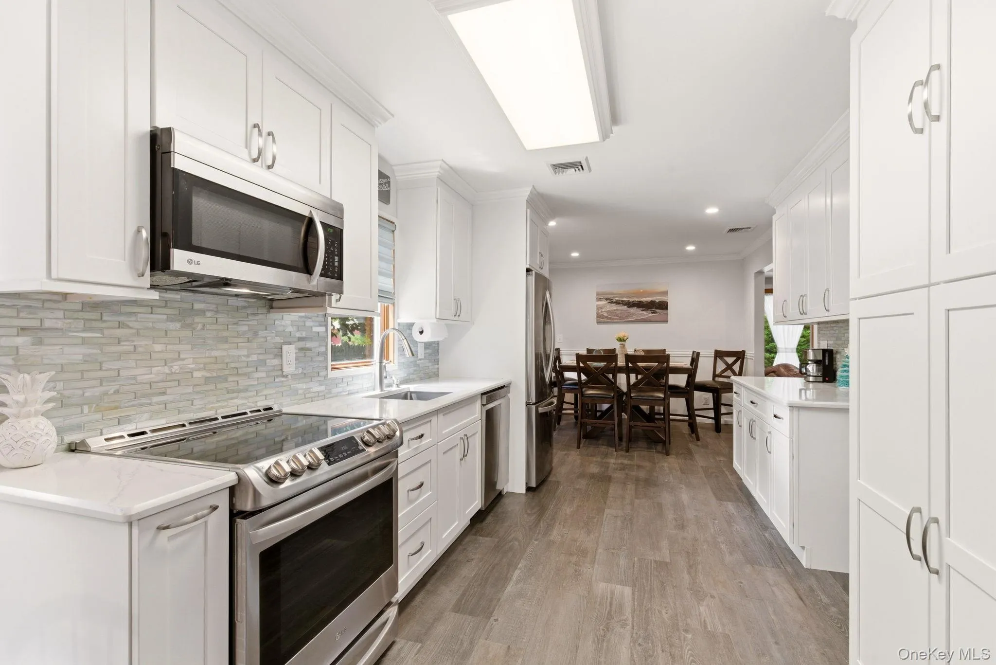 Remodeled kitchen with white cabinetry and Quartz countertops and Tommy Bahama glass tile backsplash Remodeled kitchen with white cabinetry and Quartz countertops and Tommy Bahama glass tile backsplash