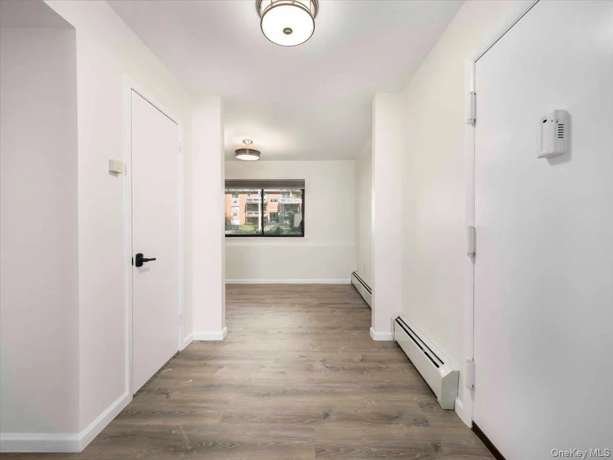 Entryway featuring light wood-finish flooring, white walls, flush-mount lighting, and baseboard heating Entryway featuring light wood-finish flooring, white walls, flush-mount lighting, and baseboard heating