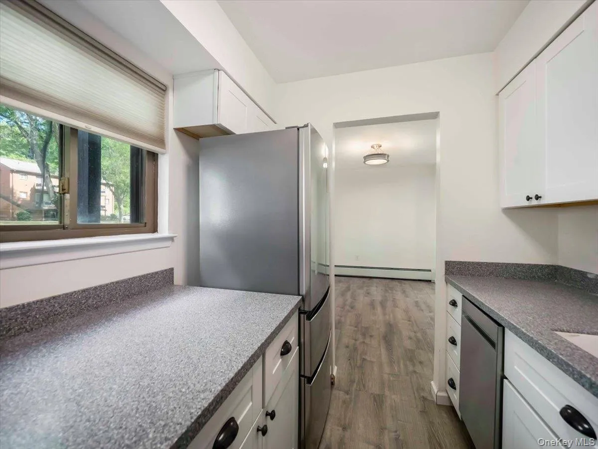 Kitchen featuring white cabinetry, speckled countertops, and stainless steel appliances Kitchen featuring white cabinetry, speckled countertops, and stainless steel appliances