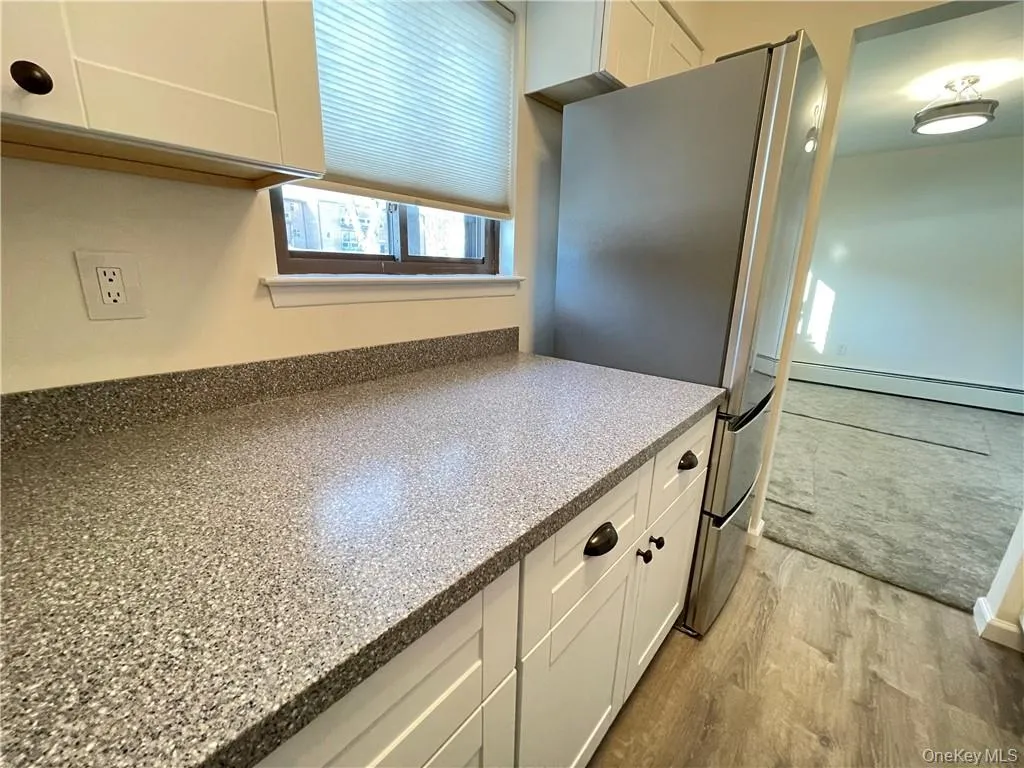 Kitchen featuring speckled countertops and white shaker-style cabinetry with dark hardware Kitchen featuring speckled countertops and white shaker-style cabinetry with dark hardware