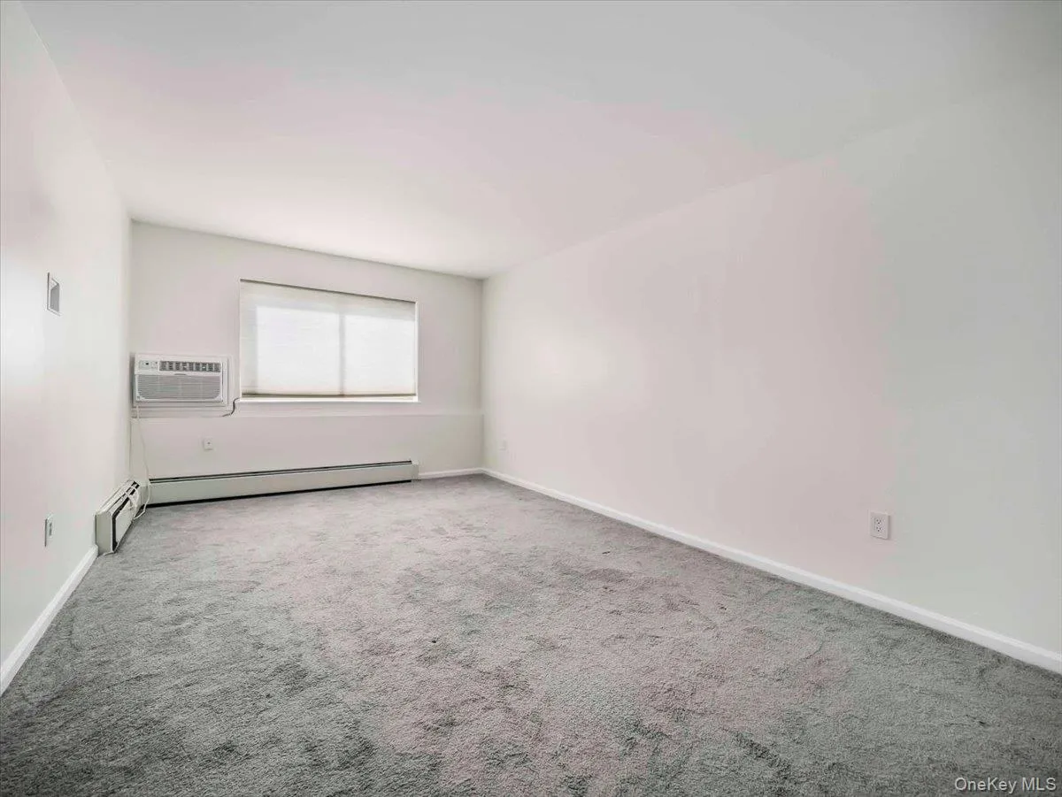 Carpeted interior space with white walls and baseboards Carpeted interior space with white walls and baseboards