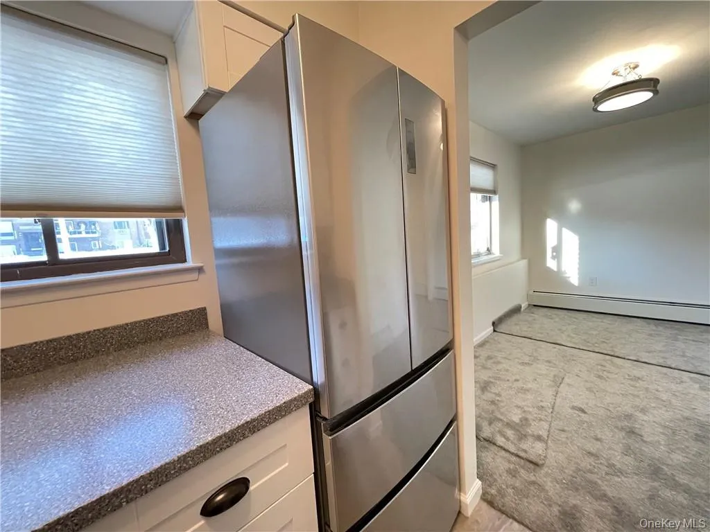 Stainless steel French door refrigerator with bottom freezer drawers, complemented by white cabinetry and a speckled countertop Stainless steel French door refrigerator with bottom freezer drawers, complemented by white cabinetry and a speckled countertop