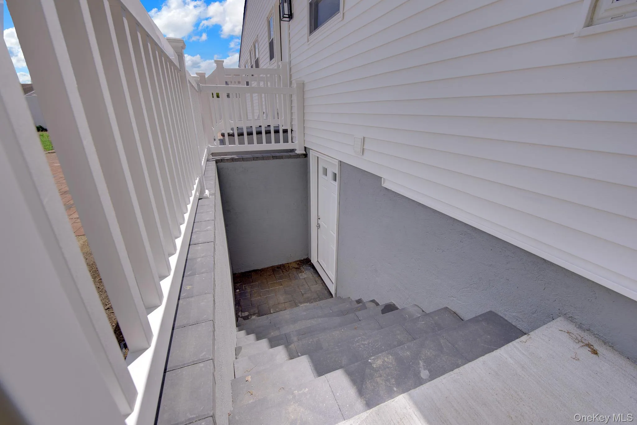 Exterior access to lower level featuring concrete steps, privacy railing, and white siding Exterior access to lower level featuring concrete steps, privacy railing, and white siding