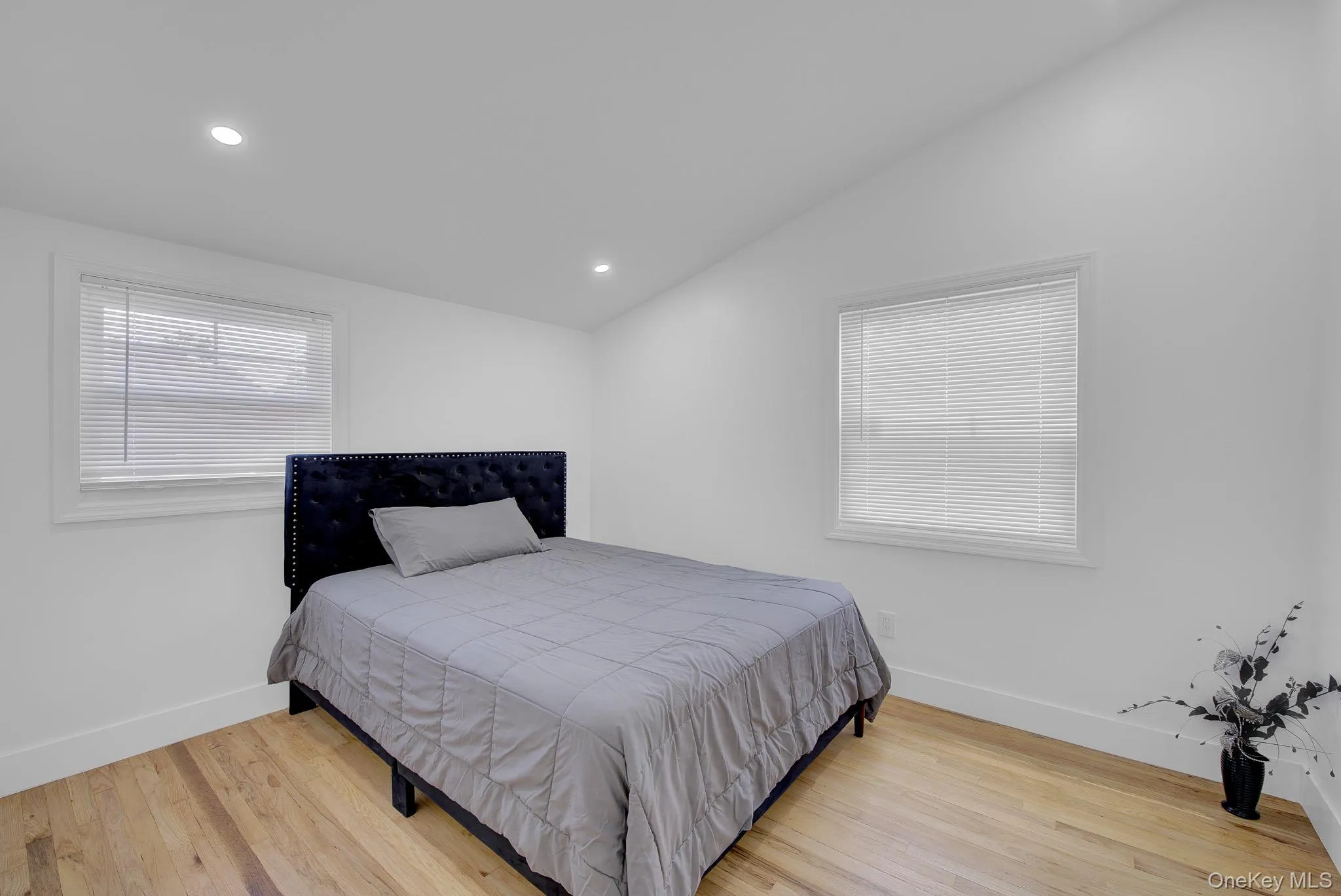 Bright room featuring wood-finish flooring, white walls, and two windows with blinds Bright room featuring wood-finish flooring, white walls, and two windows with blinds