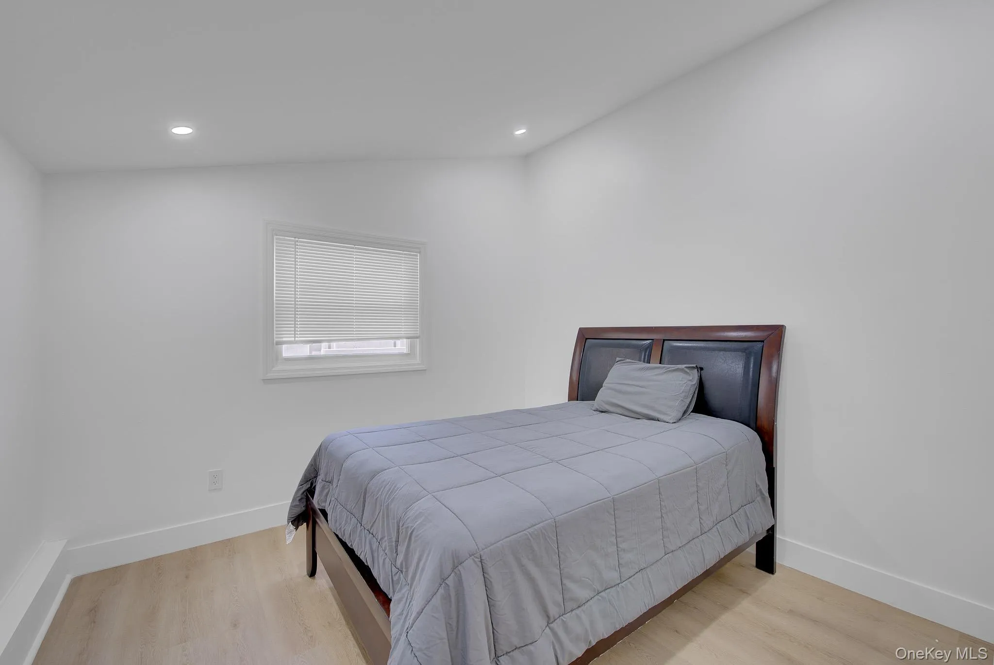Room featuring recessed lighting, light wood-finish flooring, white baseboards, and a window with blinds Room featuring recessed lighting, light wood-finish flooring, white baseboards, and a window with blinds