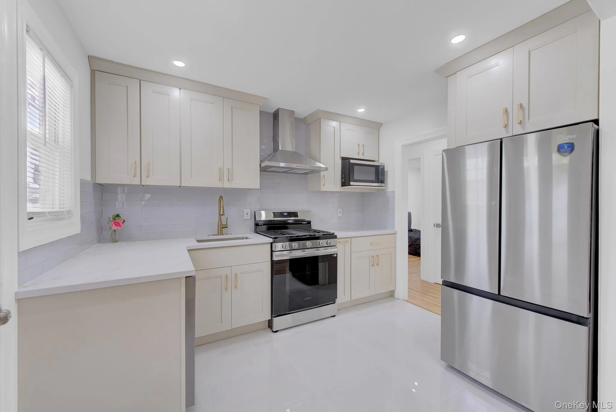 Modern kitchen featuring light-toned cabinetry, stainless steel appliances, a white countertop, and a tiled backsplash Modern kitchen featuring light-toned cabinetry, stainless steel appliances, a white countertop, and a tiled backsplash