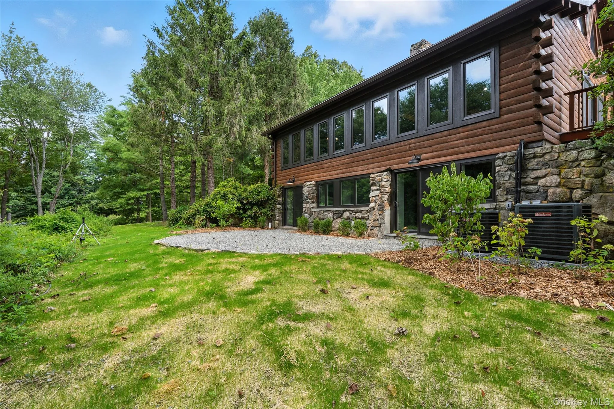 Rear view of property with stone siding, a yard, a chimney, and log exterior Rear view of property with stone siding, a yard, a chimney, and log exterior