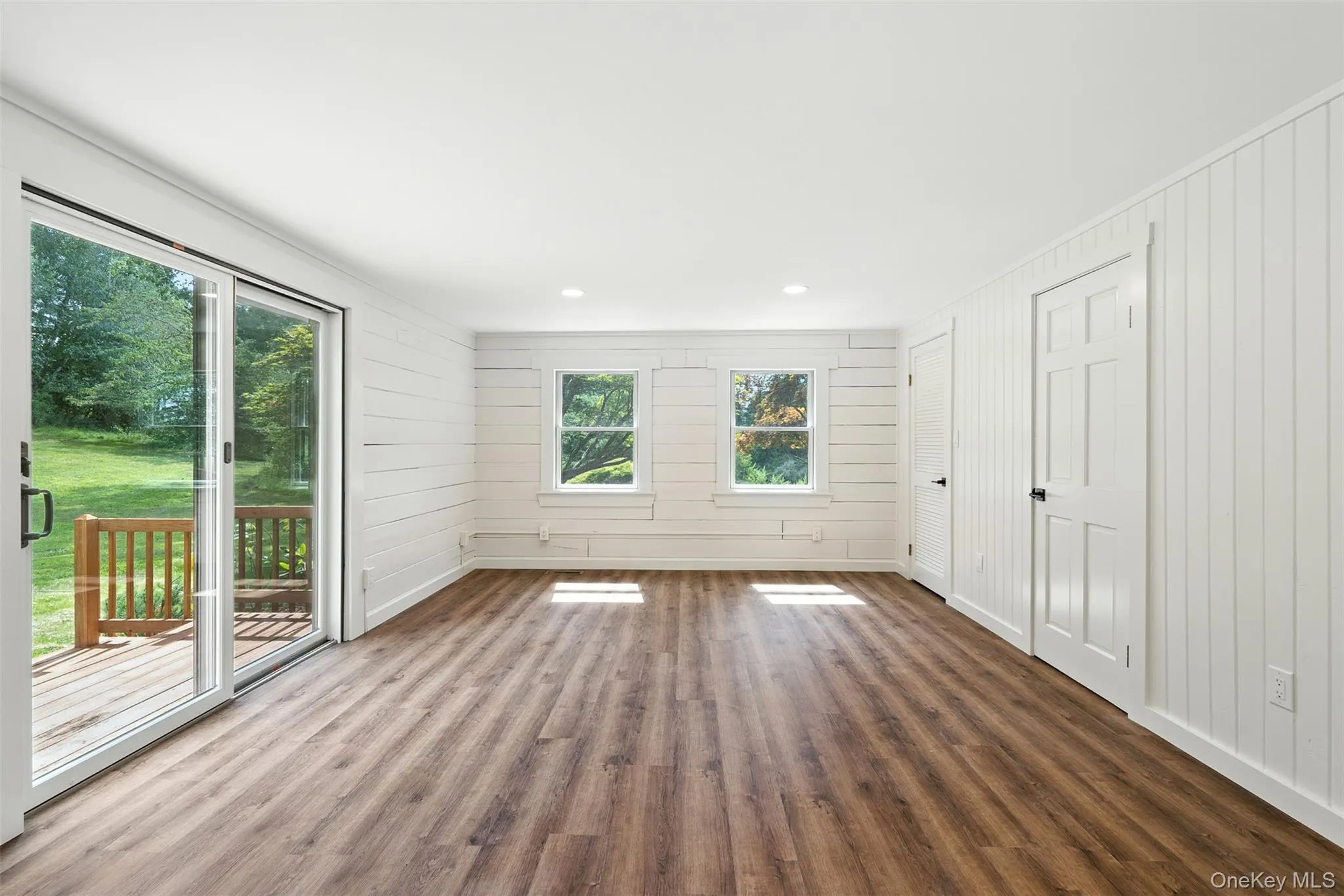 Unfurnished bedroom featuring wood finished floors, wooden walls, access to exterior, and recessed lighting Unfurnished bedroom featuring wood finished floors, wooden walls, access to exterior, and recessed lighting