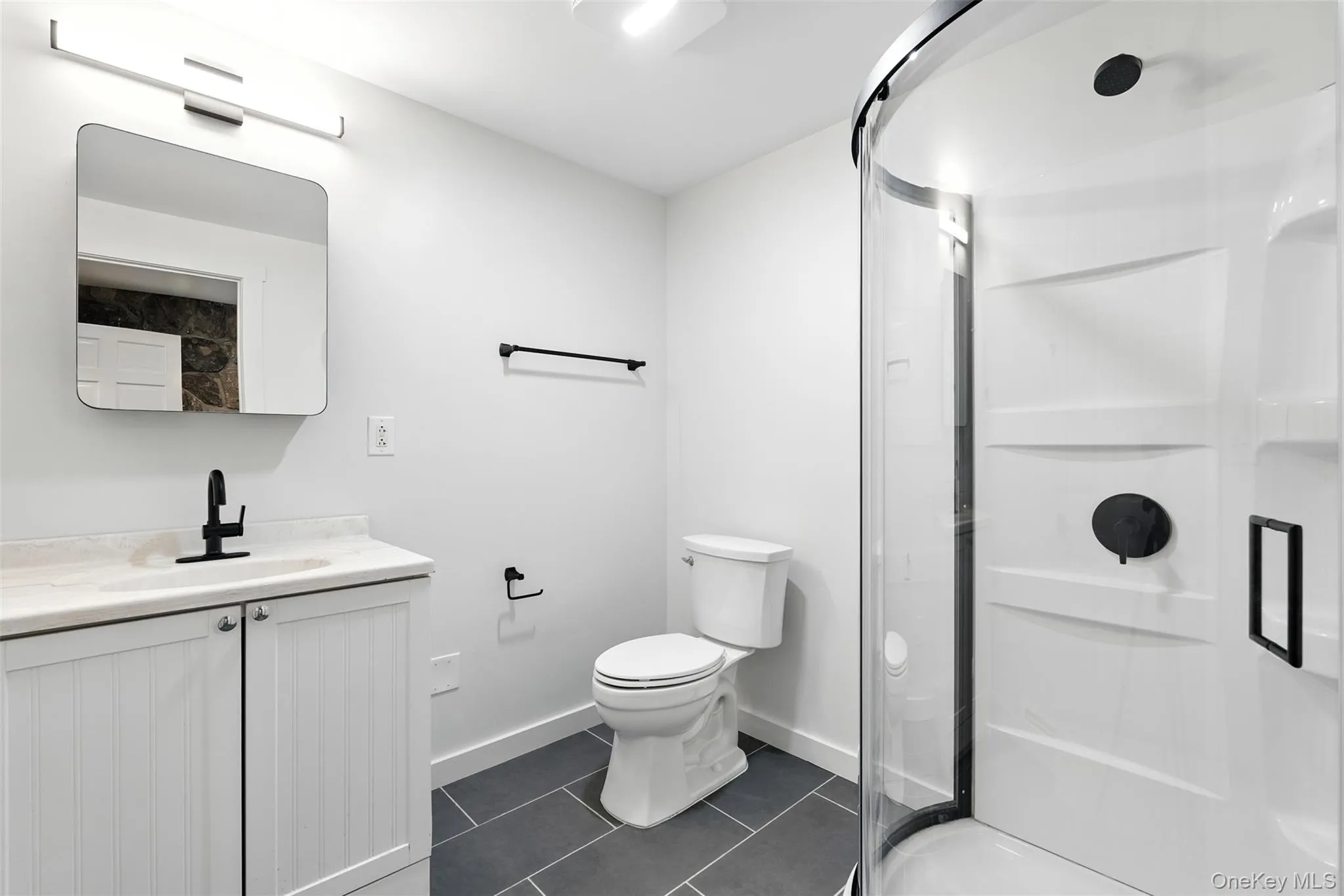Full bath with vanity, a shower stall, and dark tile patterned flooring Full bath with vanity, a shower stall, and dark tile patterned flooring