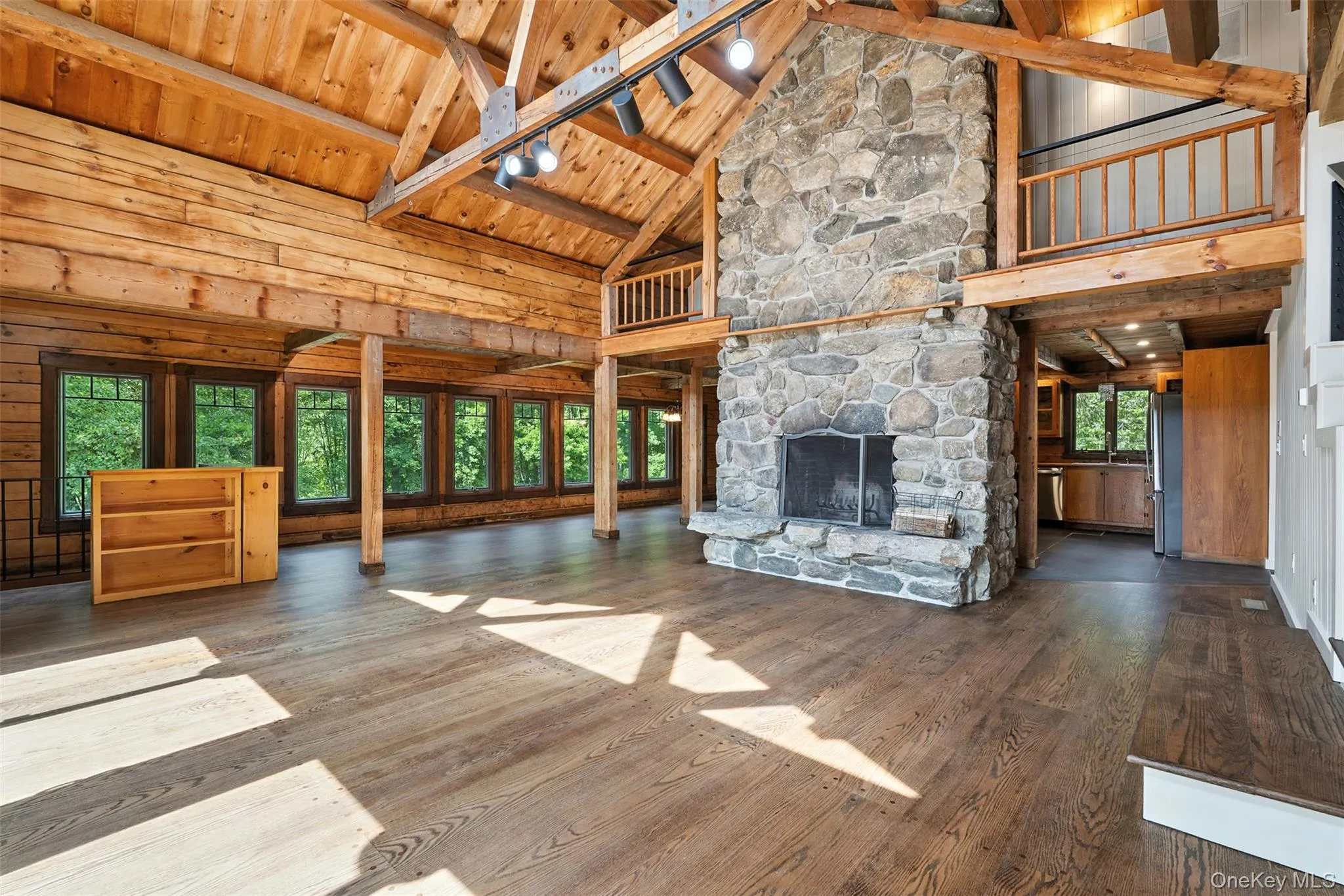 Unfurnished living room with high vaulted ceiling, a fireplace, hardwood / wood-style floors, wood walls, and a wood ceiling with exposed beams Unfurnished living room with high vaulted ceiling, a fireplace, hardwood / wood-style floors, wood walls, and a wood ceiling with exposed beams
