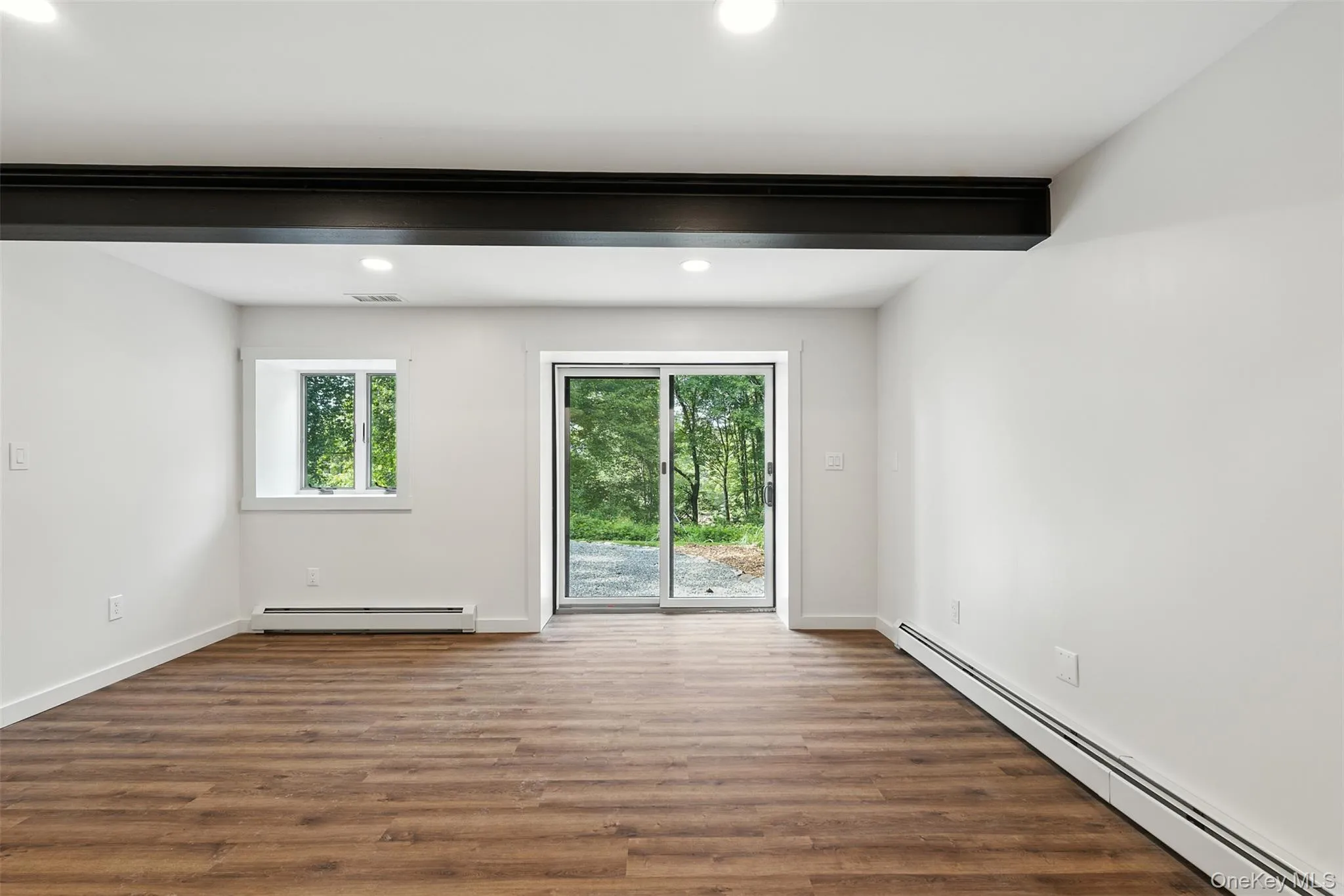 Empty room featuring a baseboard heating unit, wood finished floors, and recessed lighting Empty room featuring a baseboard heating unit, wood finished floors, and recessed lighting