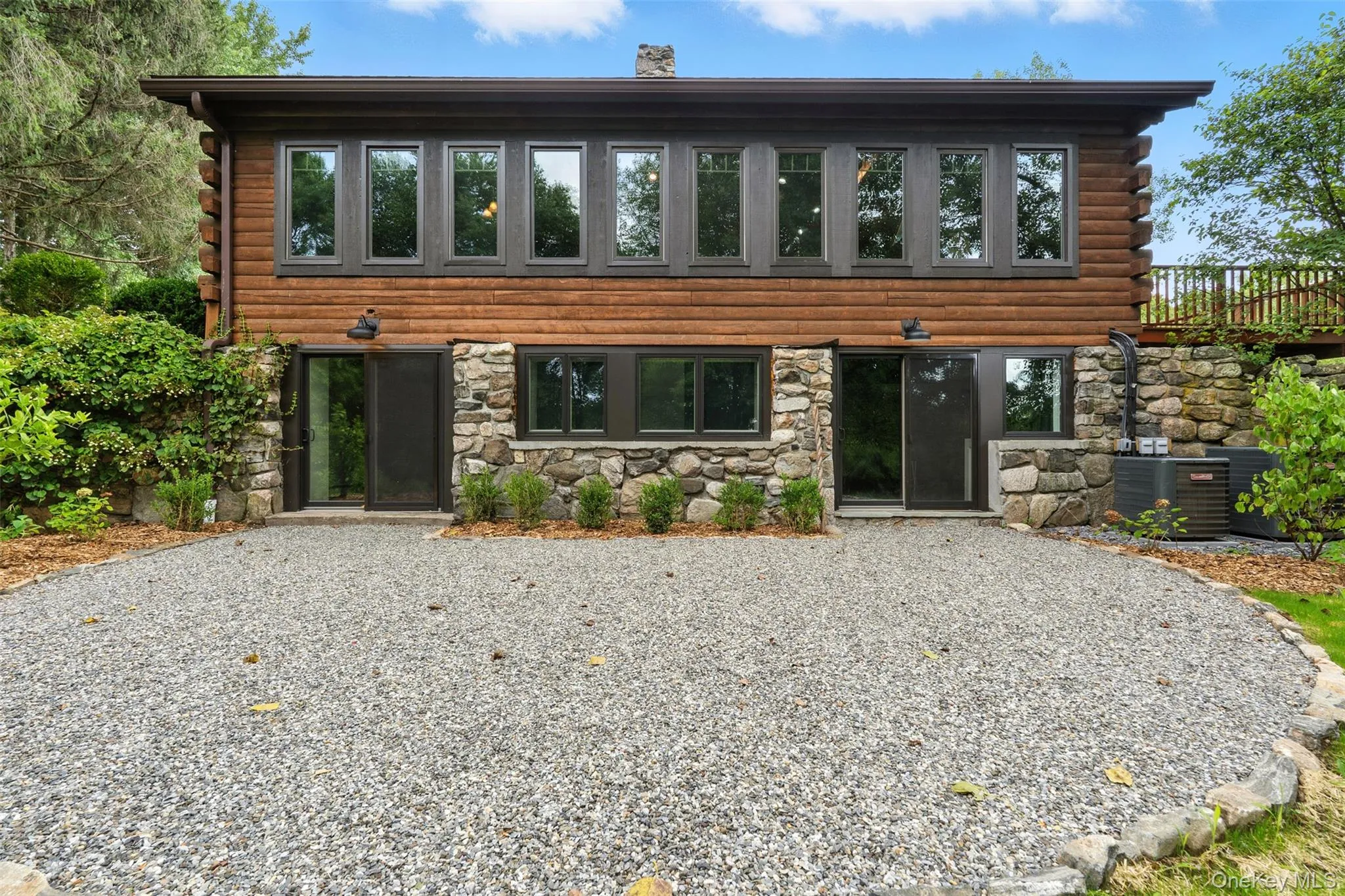 Rear view of house featuring log siding, stone siding, and a chimney Rear view of house featuring log siding, stone siding, and a chimney