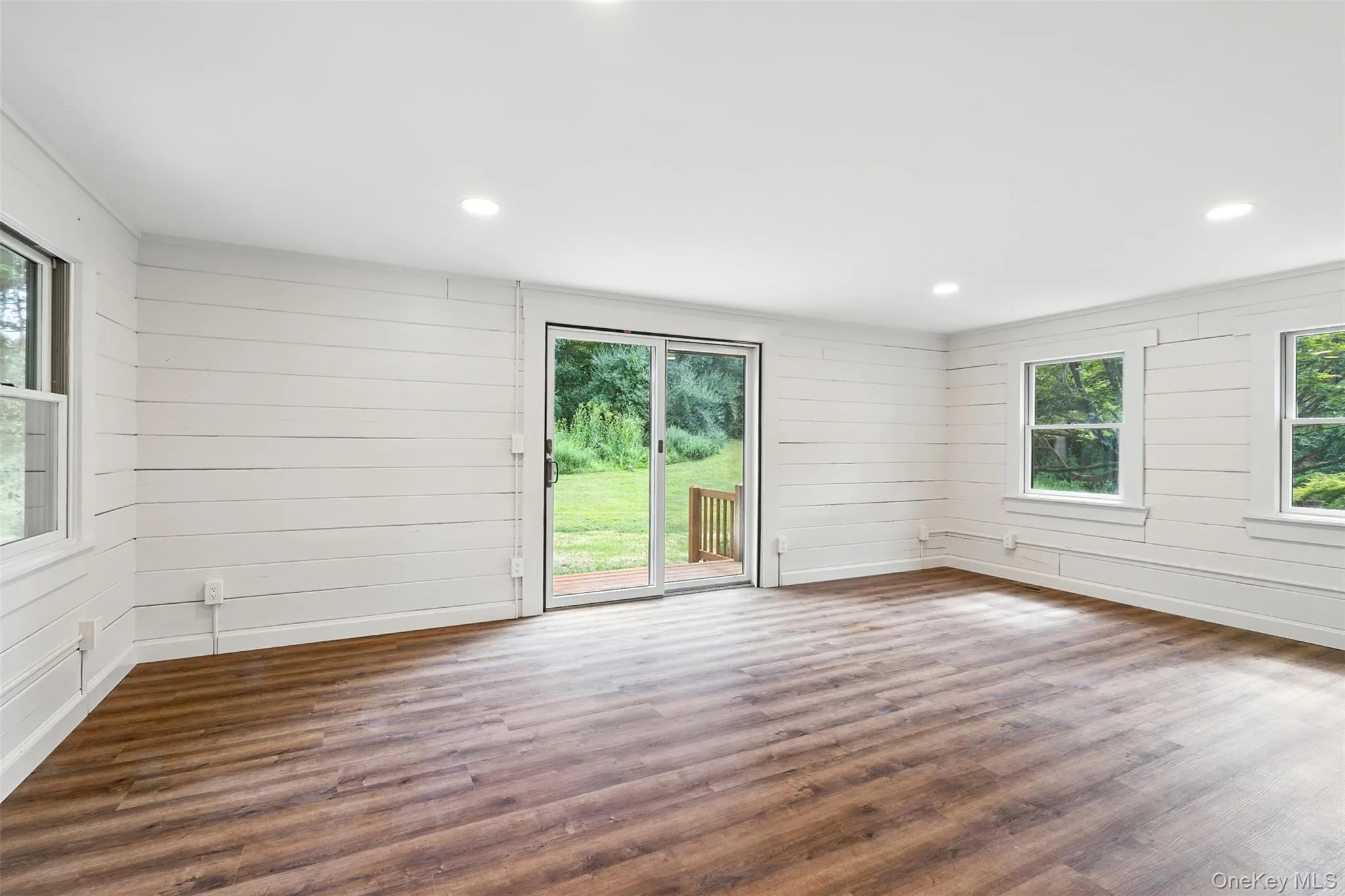 Unfurnished room with wood finished floors, wood walls, and recessed lighting Unfurnished room with wood finished floors, wood walls, and recessed lighting